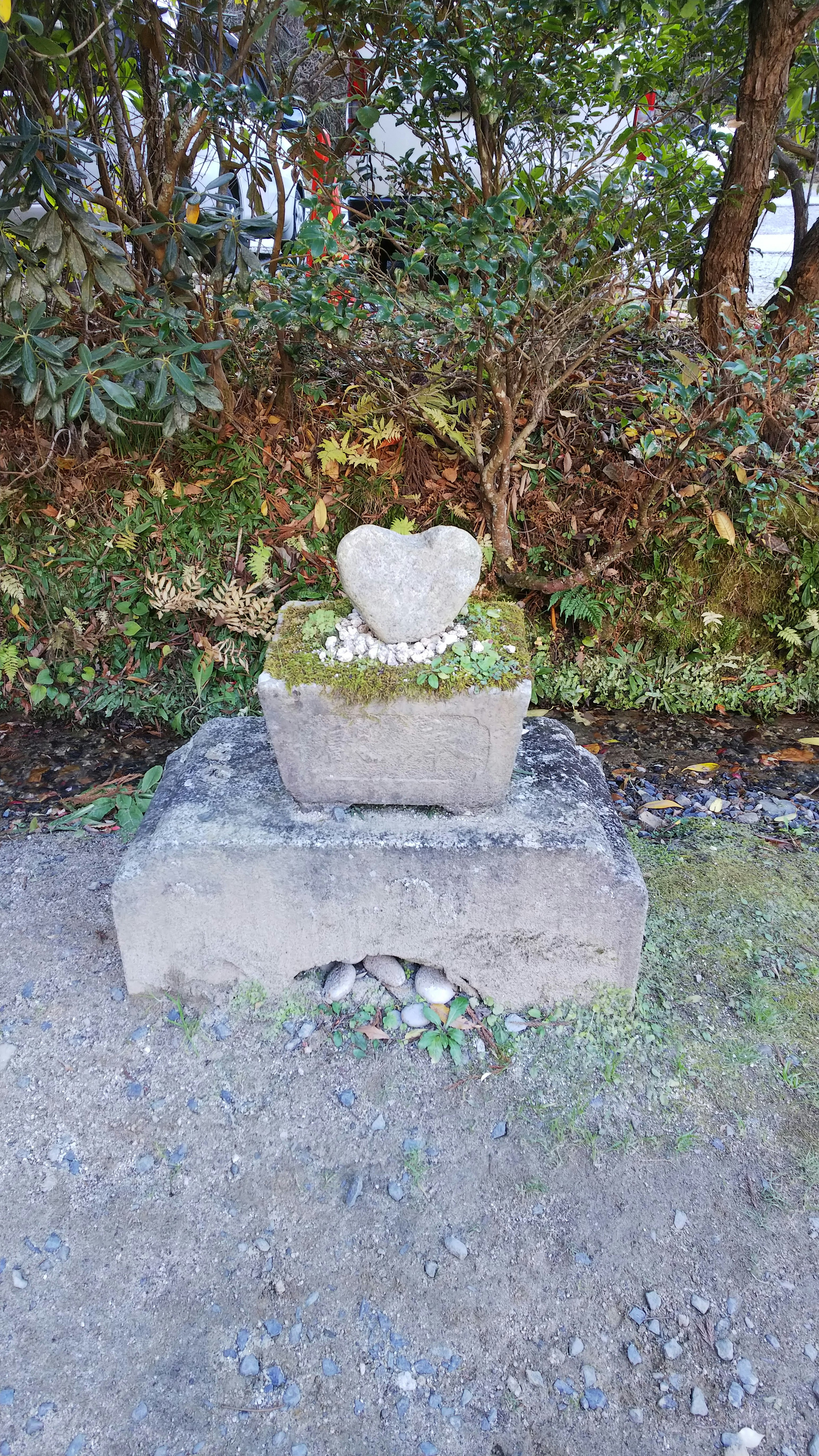 庭の石積みの小さな祠と花