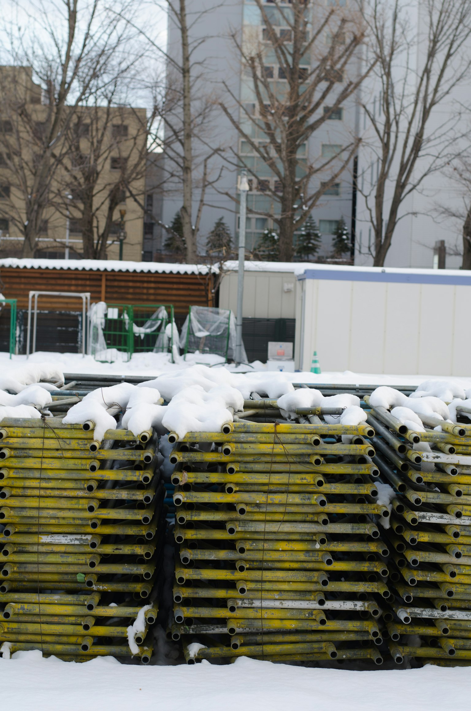 雪中堆叠的黄色脚手架和周围建筑