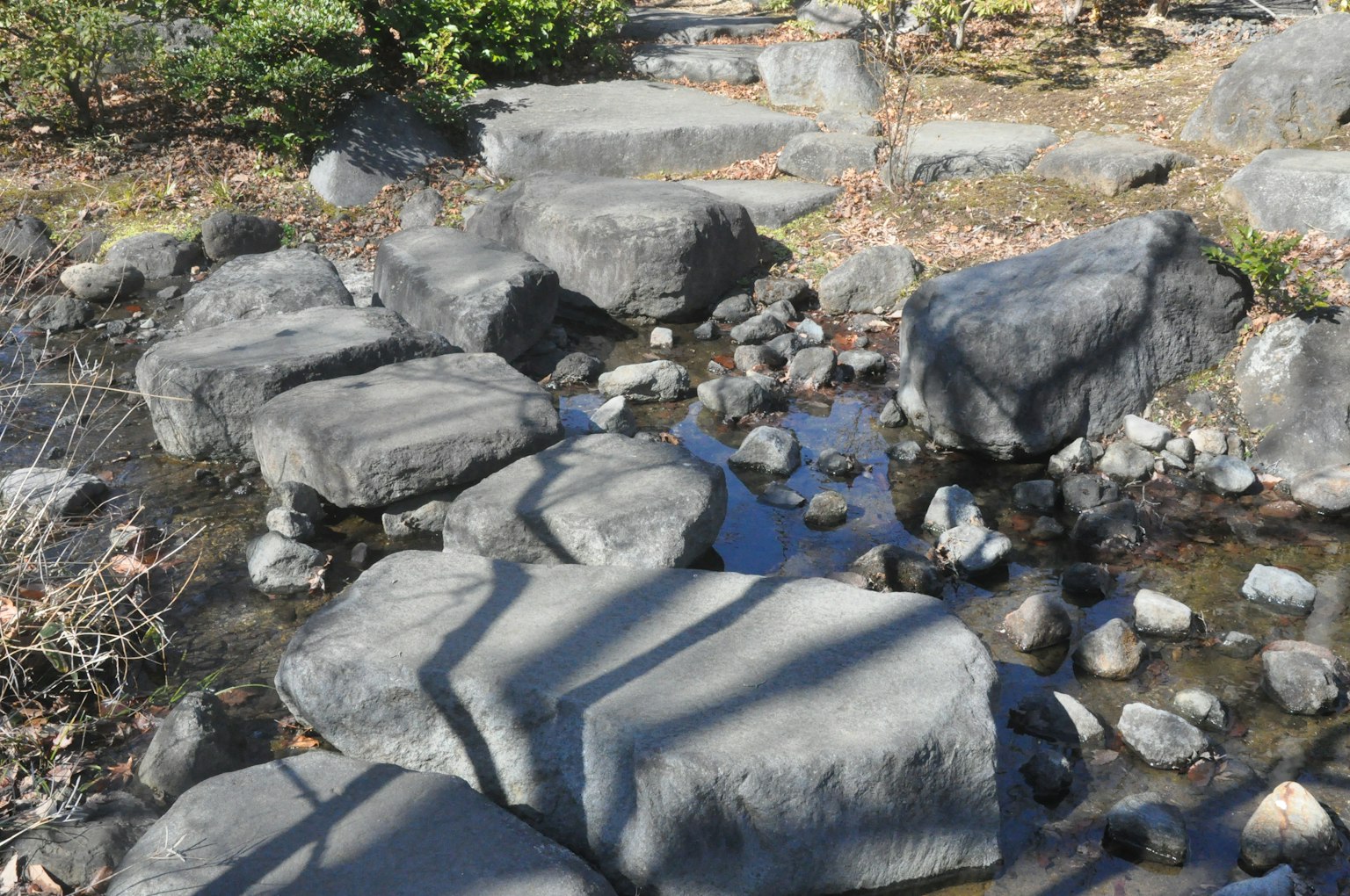 Vue d'un étang de jardin japonais avec des rochers et des galets