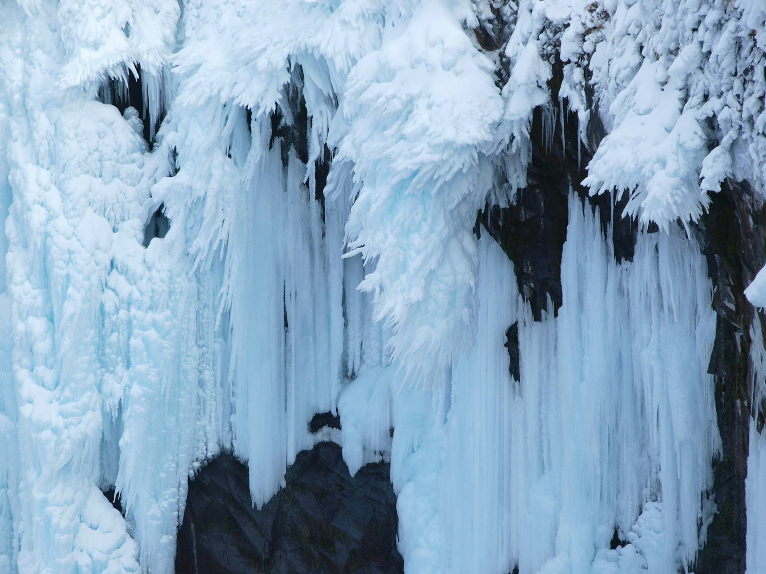Primo piano di una cascata di ghiaccio con strati di ghiaccio su rocce scure