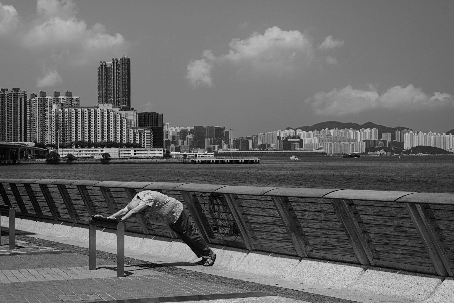 Man doing push-ups by the waterfront with skyscrapers in the background