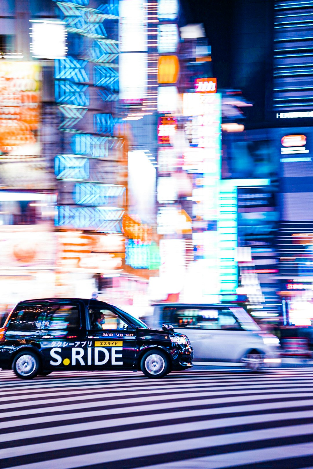 ネオンの街並みを走るタクシーと車の流れ