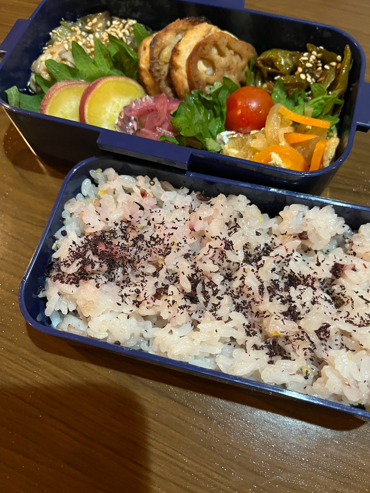 Hộp bento màu xanh chứa cơm và các nguyên liệu đầy màu sắc