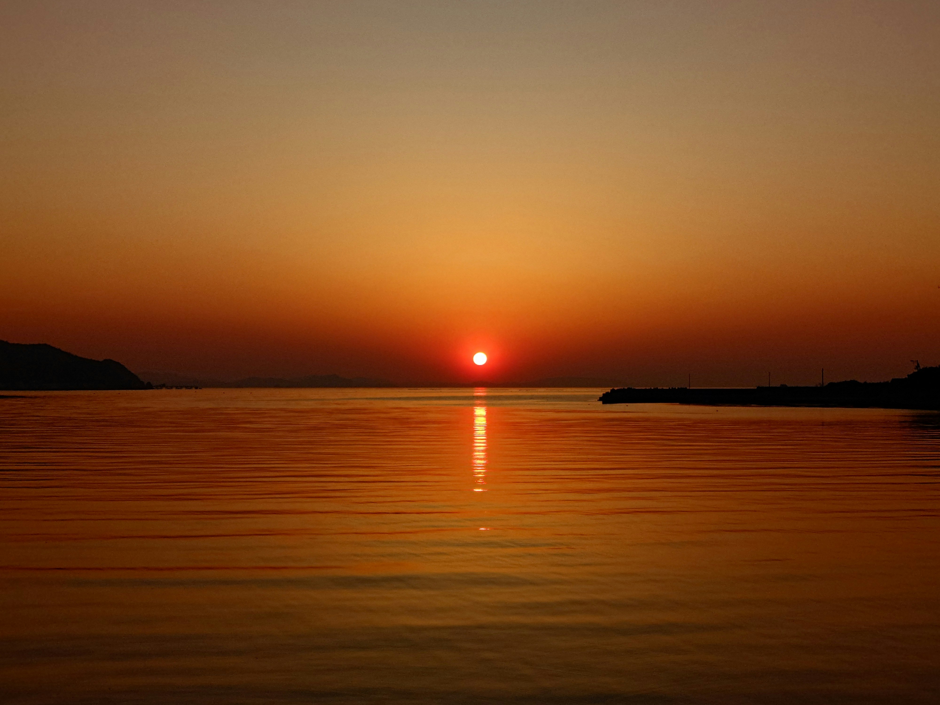 水平線に沈む夕日が映る海面の風景