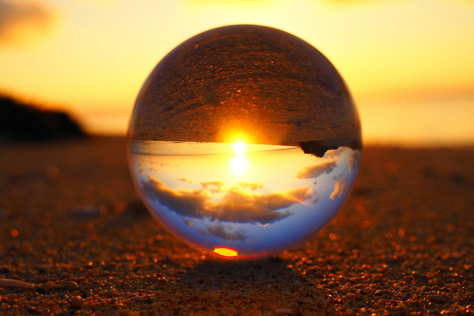 A crystal ball reflecting the sunset on a sandy beach
