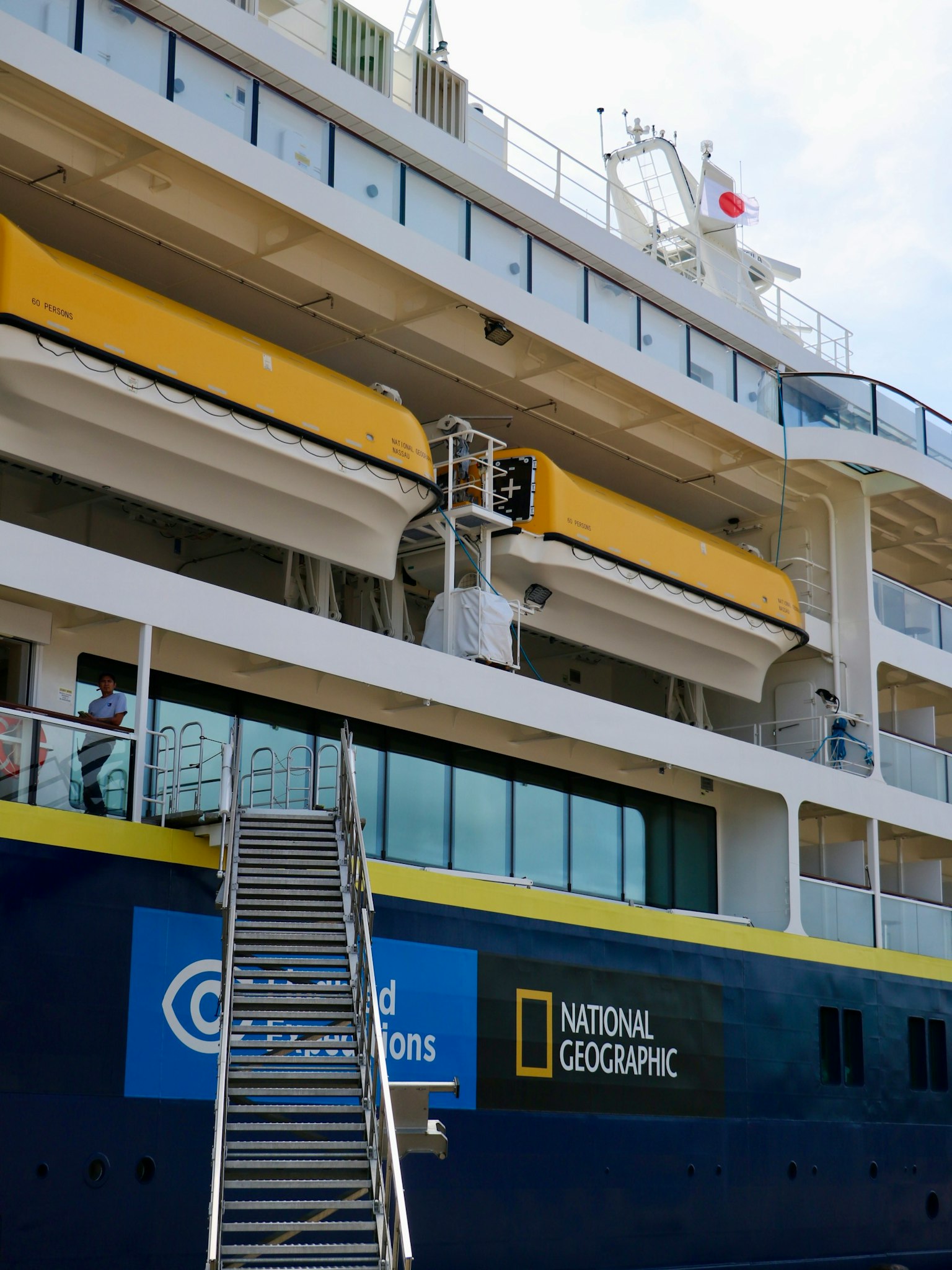 Vista laterale di una nave da crociera National Geographic con una striscia gialla e una scala