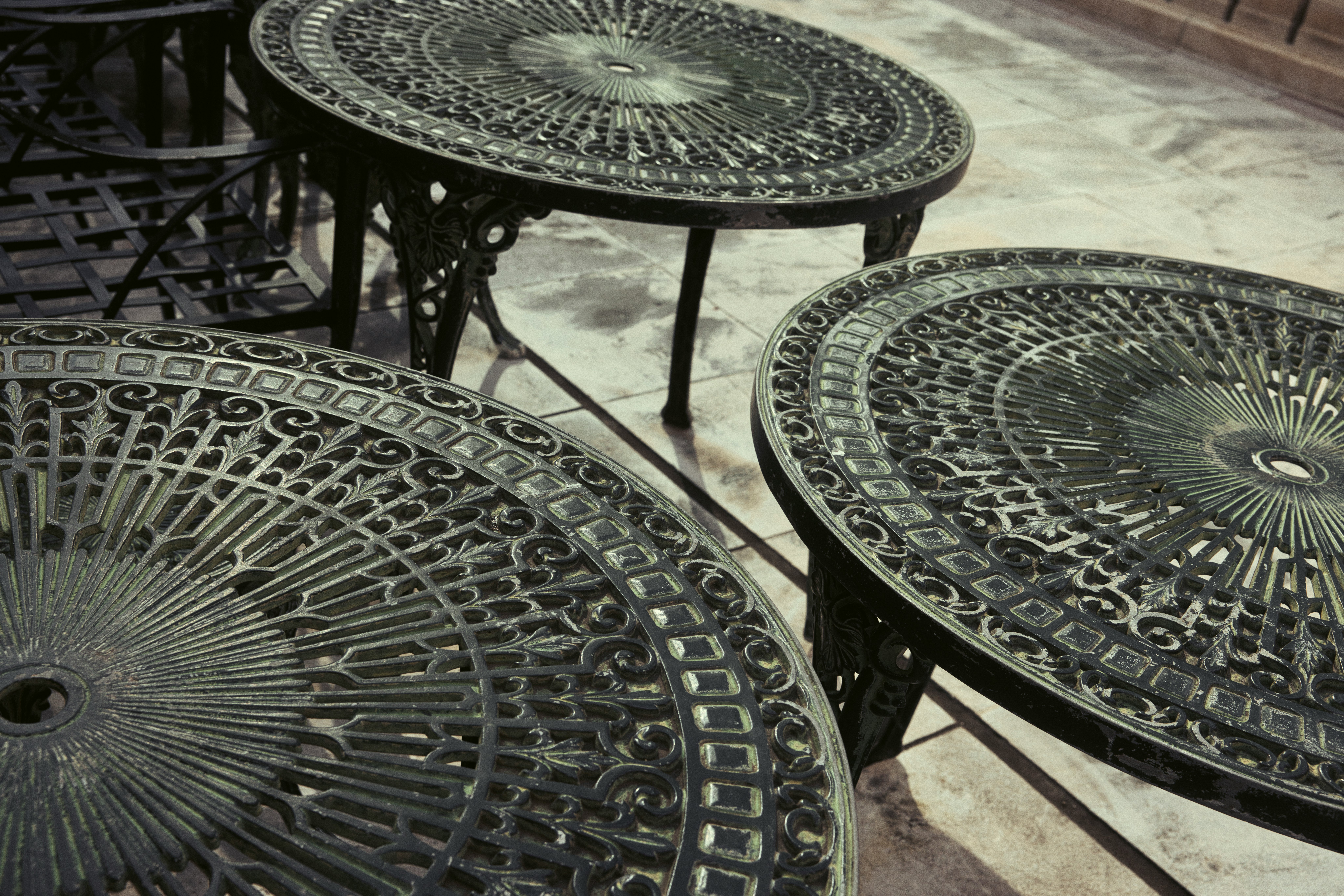 mesas y sillas metálicas ornamentadas en una terraza exterior