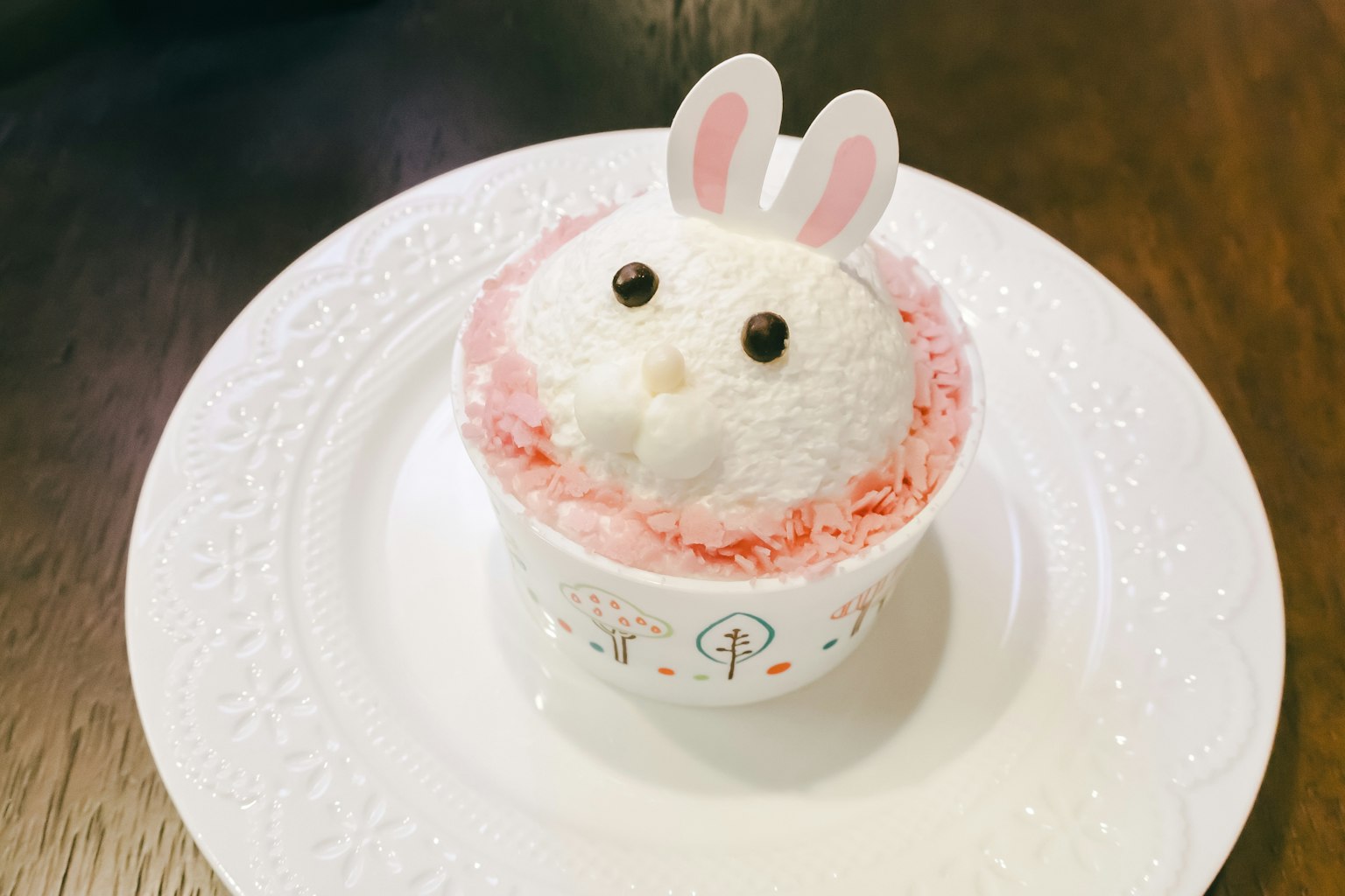 Dessert a forma di coniglio decorato con crema rosa su un piatto bianco