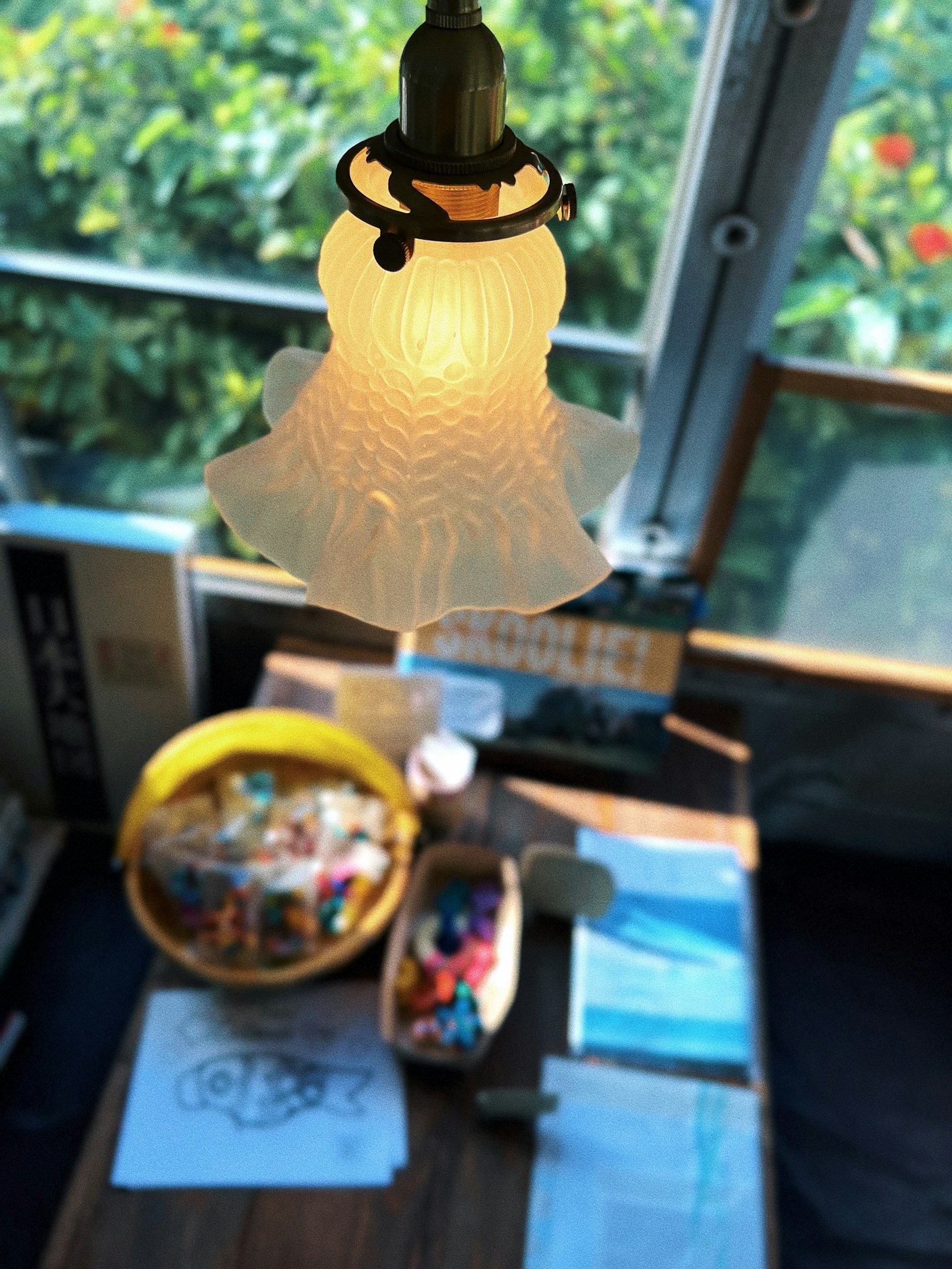 Eine Ansicht mit einer bunten Auswahl an Kunstmaterialien auf einem Tisch unter einer dekorativen Lampe