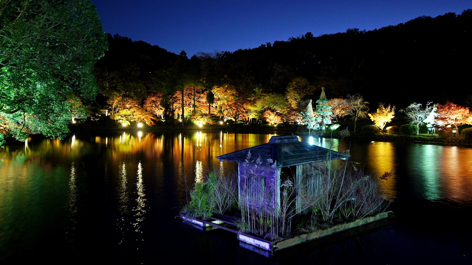 Capanna galleggiante su un lago di notte con luci colorate intorno
