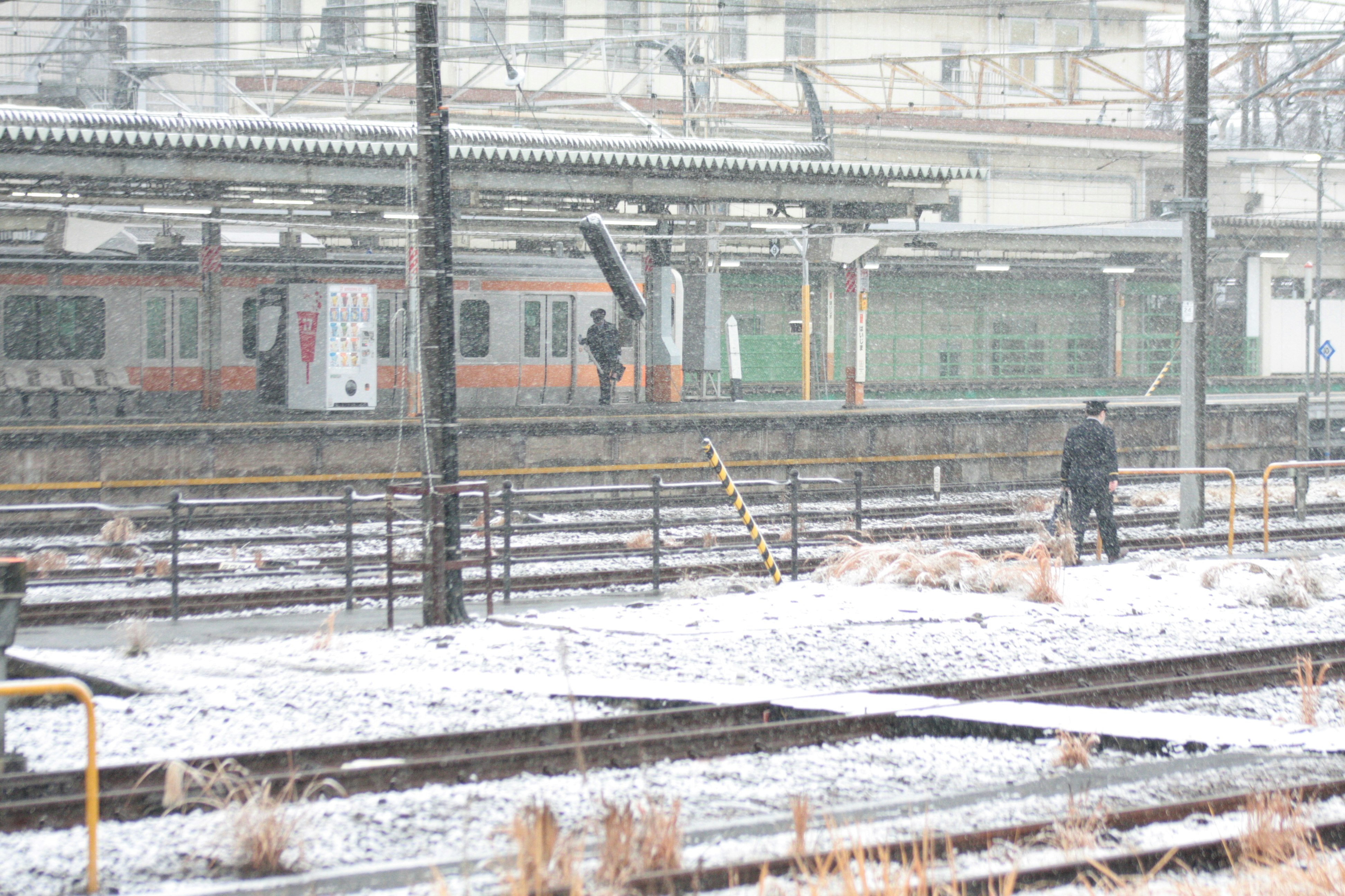 雪の降る線路と電車が並ぶ駅のホーム