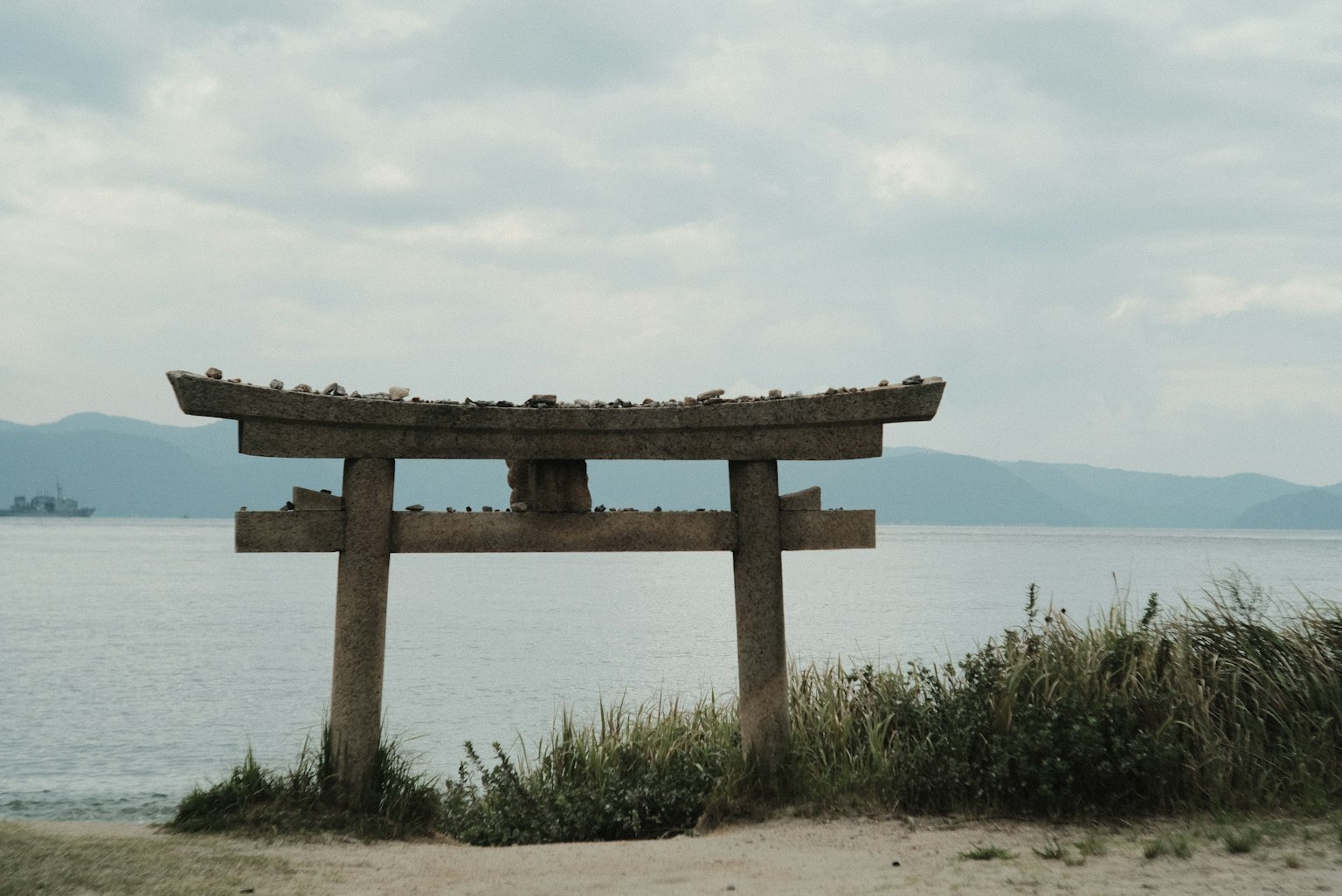 Alter Torii, das zum Meer zeigt, mit einer grasbewachsenen Fläche