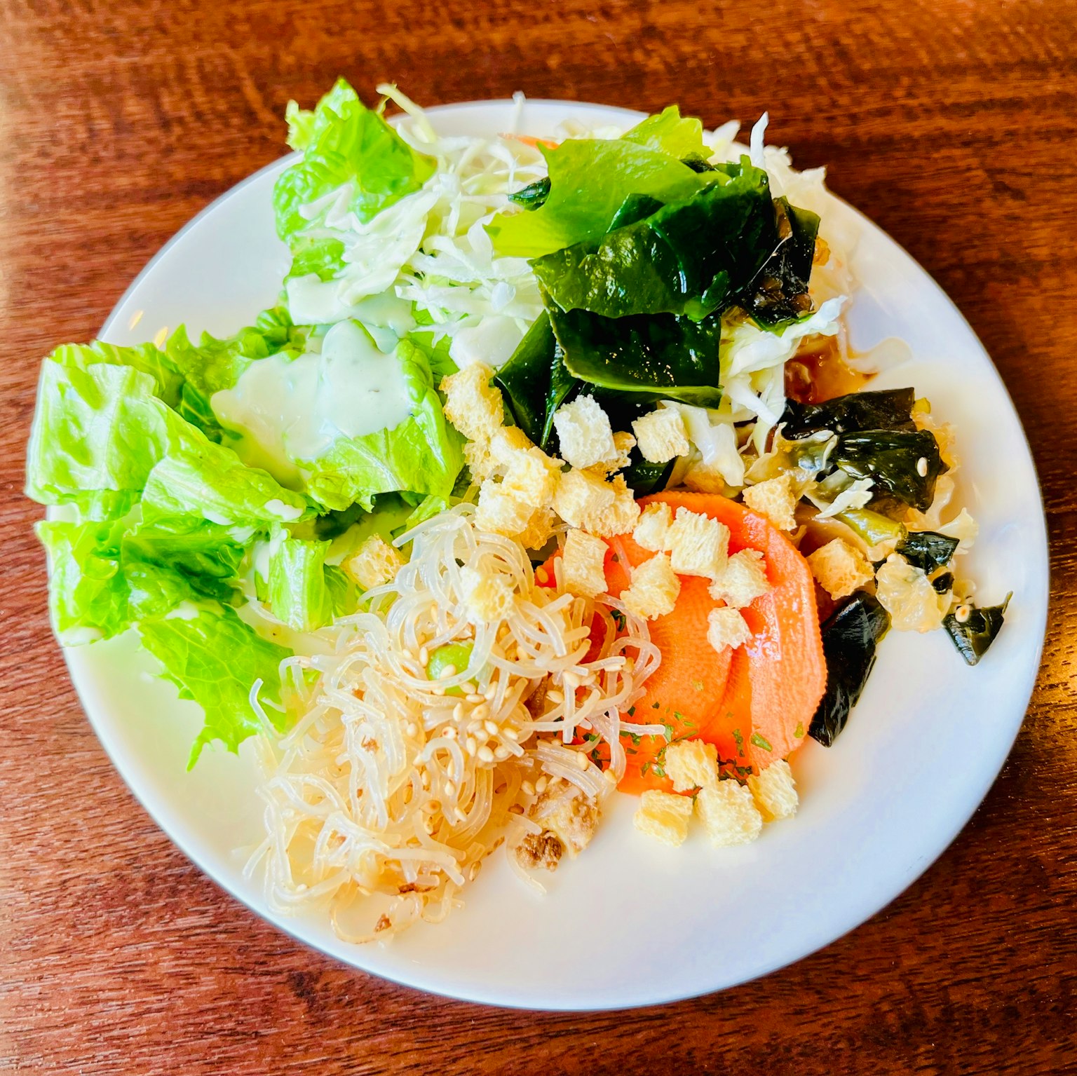 Ein Teller frischer Salat mit Salat, Kohl, Algen, Tomate und Croutons