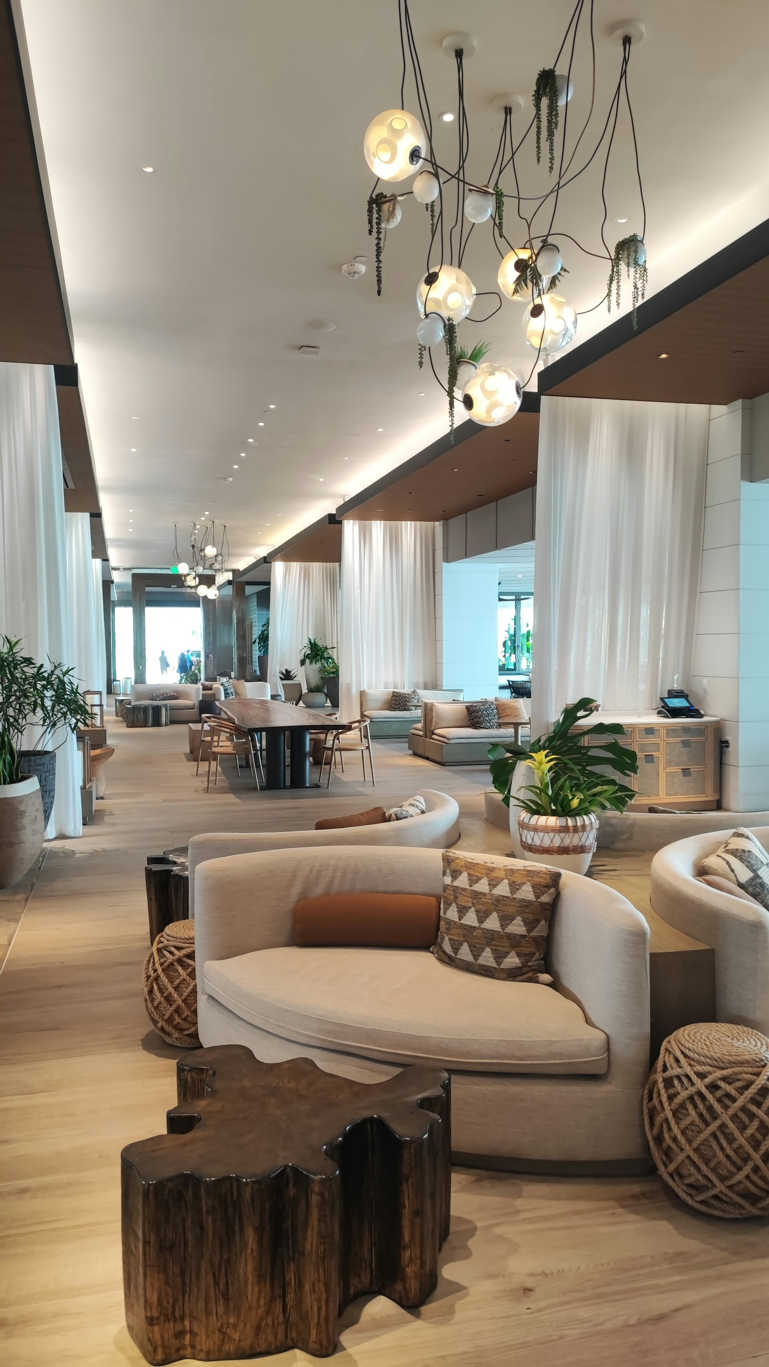 Area lounge modern dengan sofa lembut, meja kayu, dan tanaman dekoratif