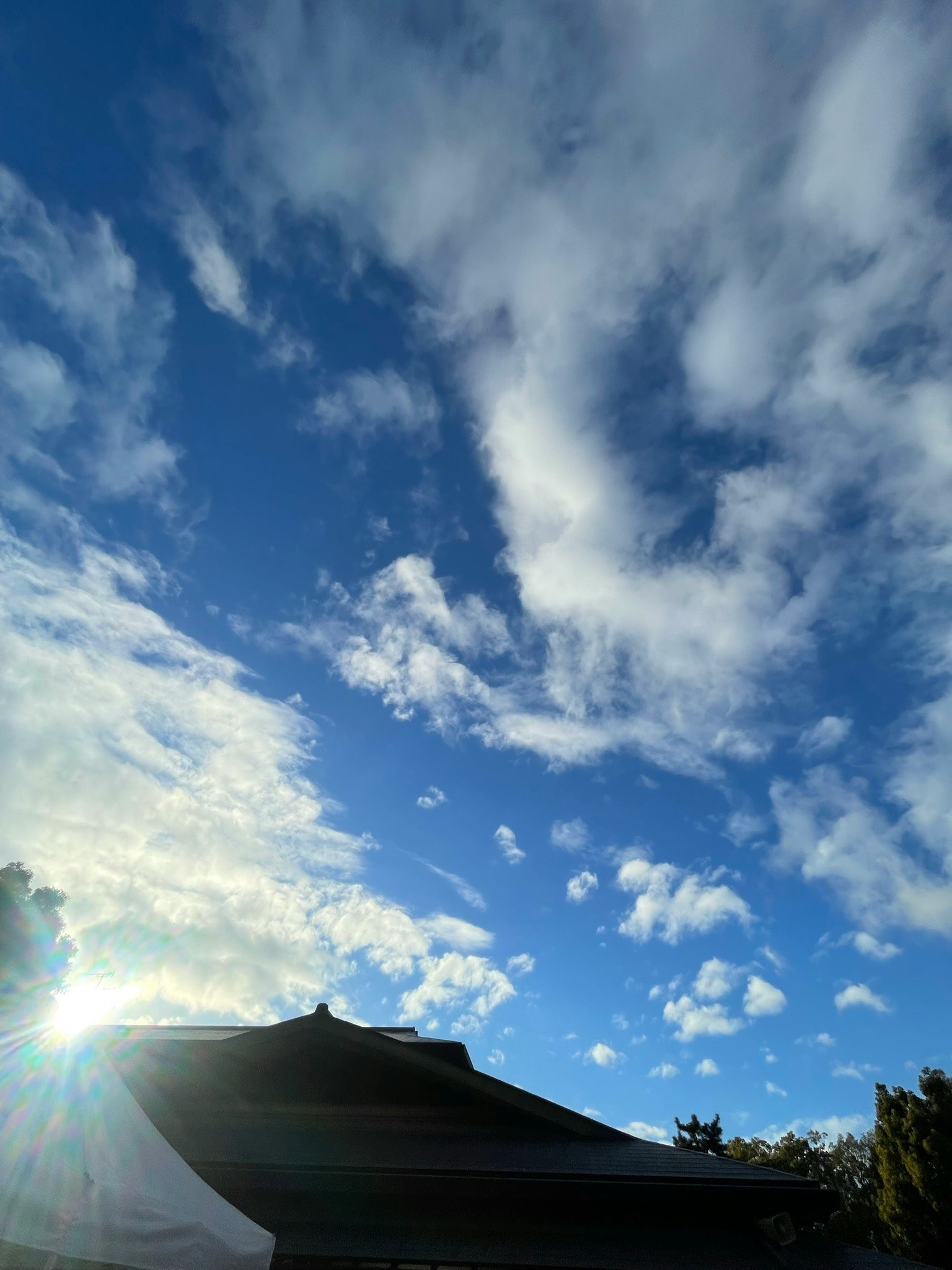 Cielo azul claro con nubes blancas y un techo de edificio