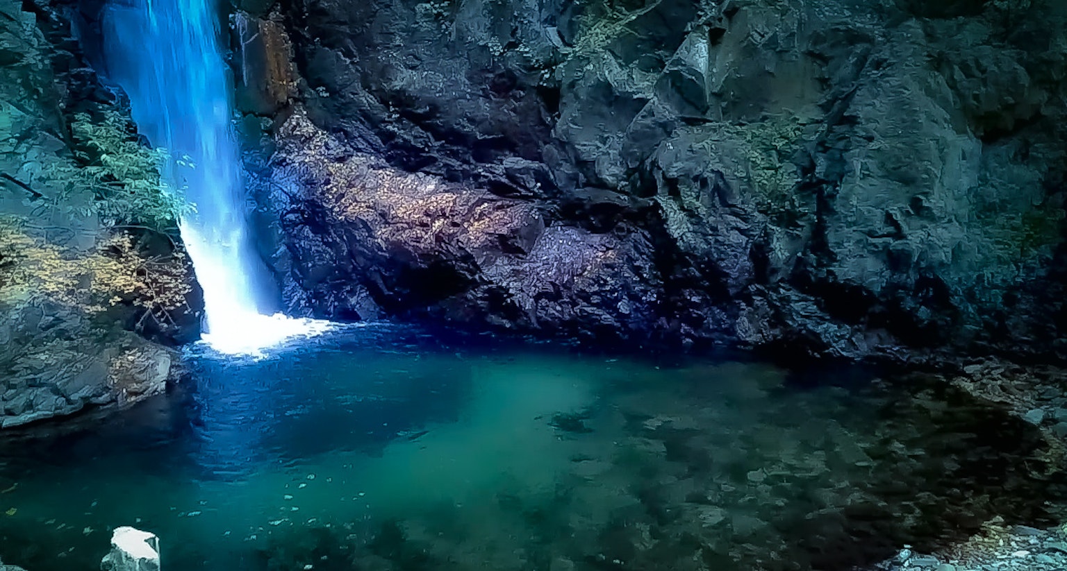 Ein schöner Wasserfall, der in einen türkisfarbenen Pool fließt, umgeben von felsigen Klippen