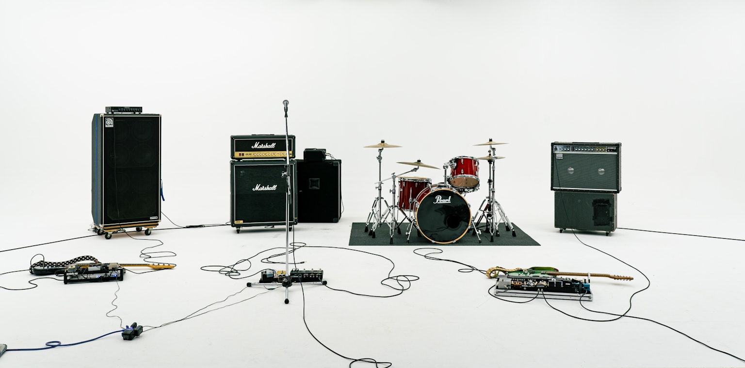 Pengaturan peralatan musik di latar belakang putih dengan tiang mikrofon set drum gitar dan amplifier
