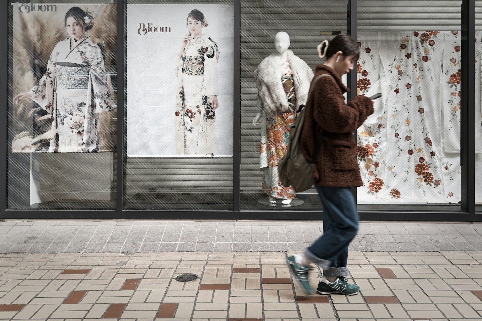 Una joven caminando por la calle con exhibiciones de kimono en la vitrina