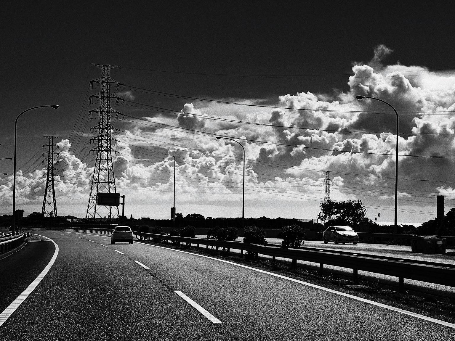 Black and white highway with expansive clouds in the sky