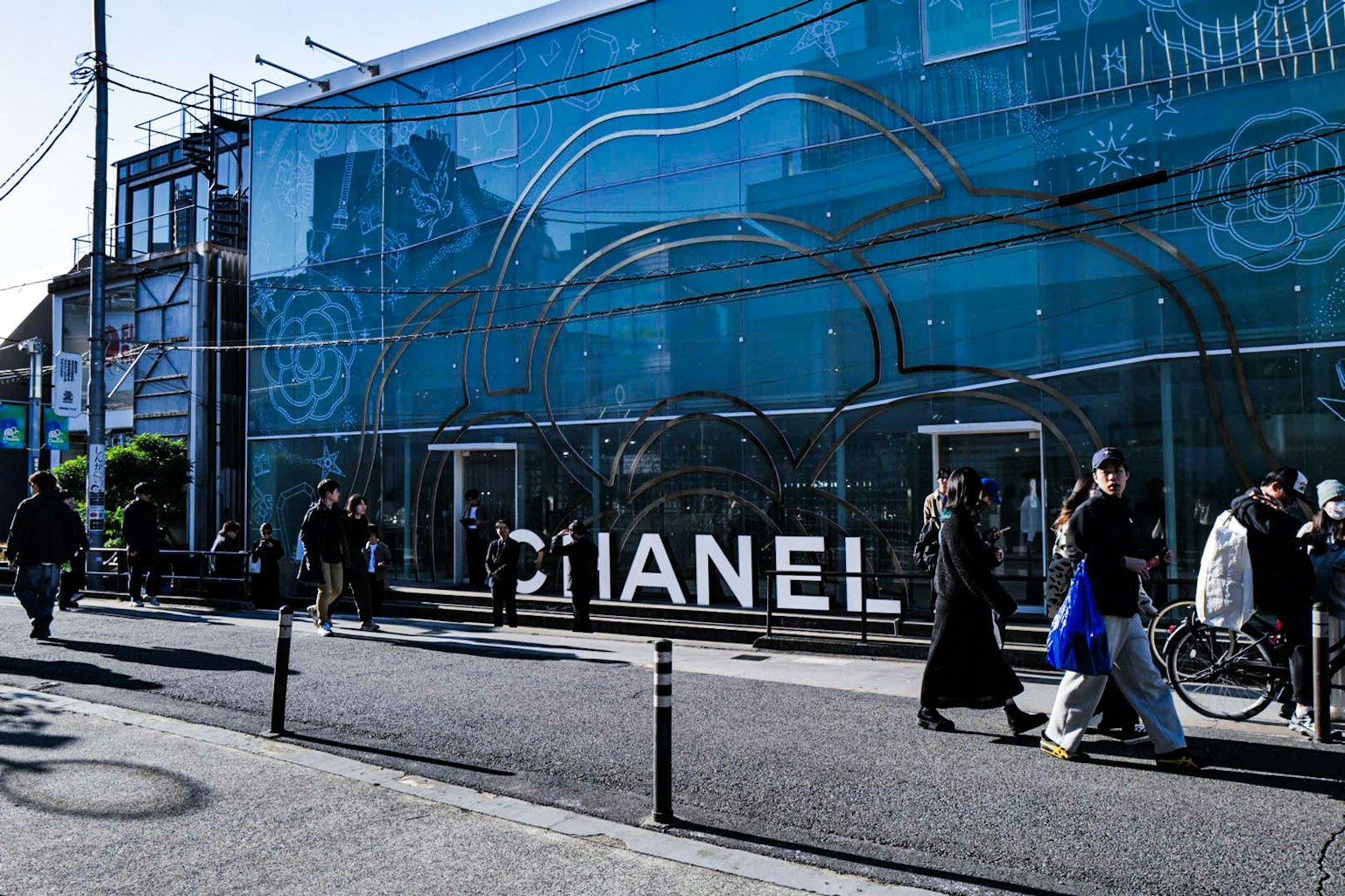 青い壁に大きなシャネルのロゴが描かれた店舗の前に人々が集まっている