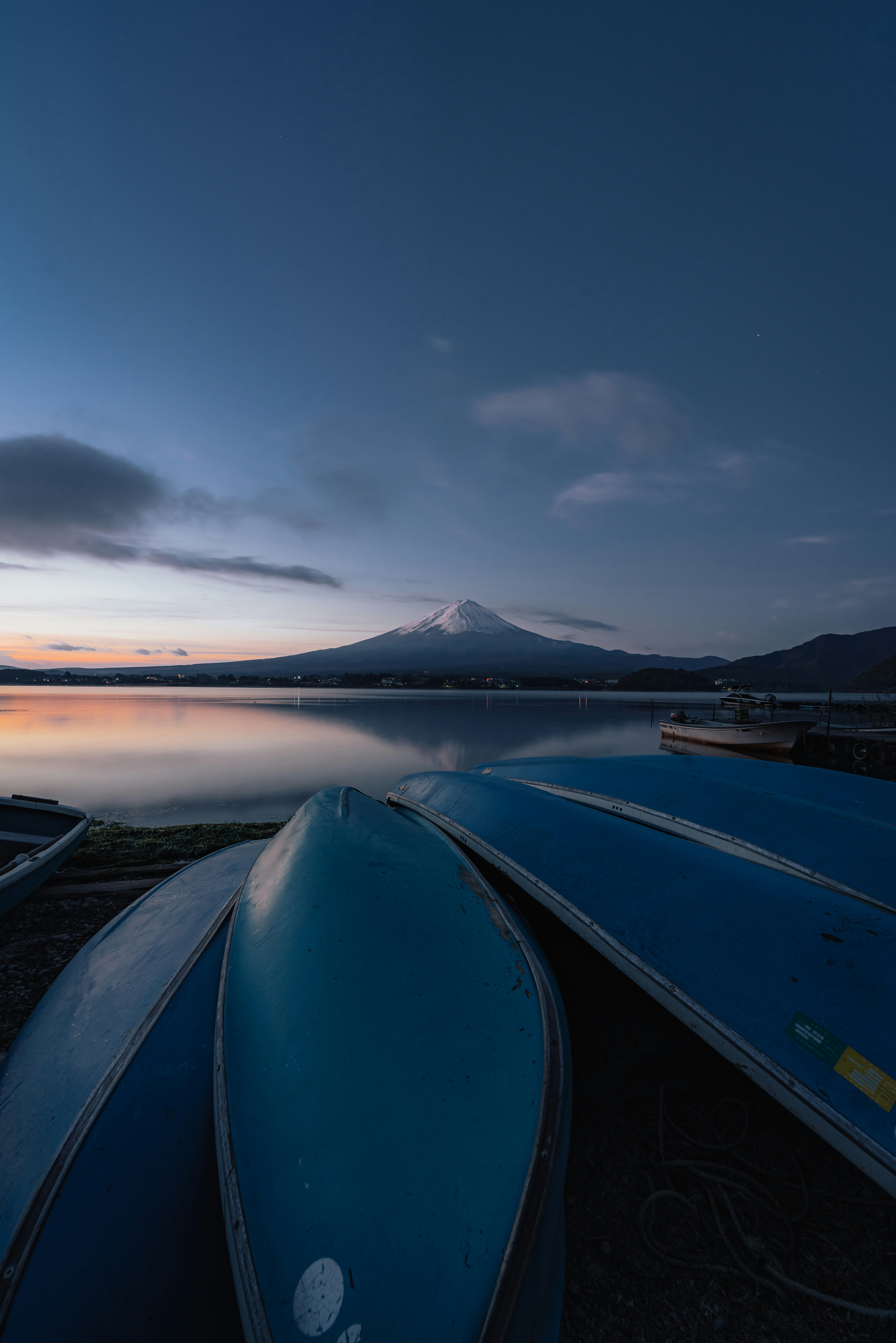 夕暮れの湖畔に並ぶボートと遠くの山