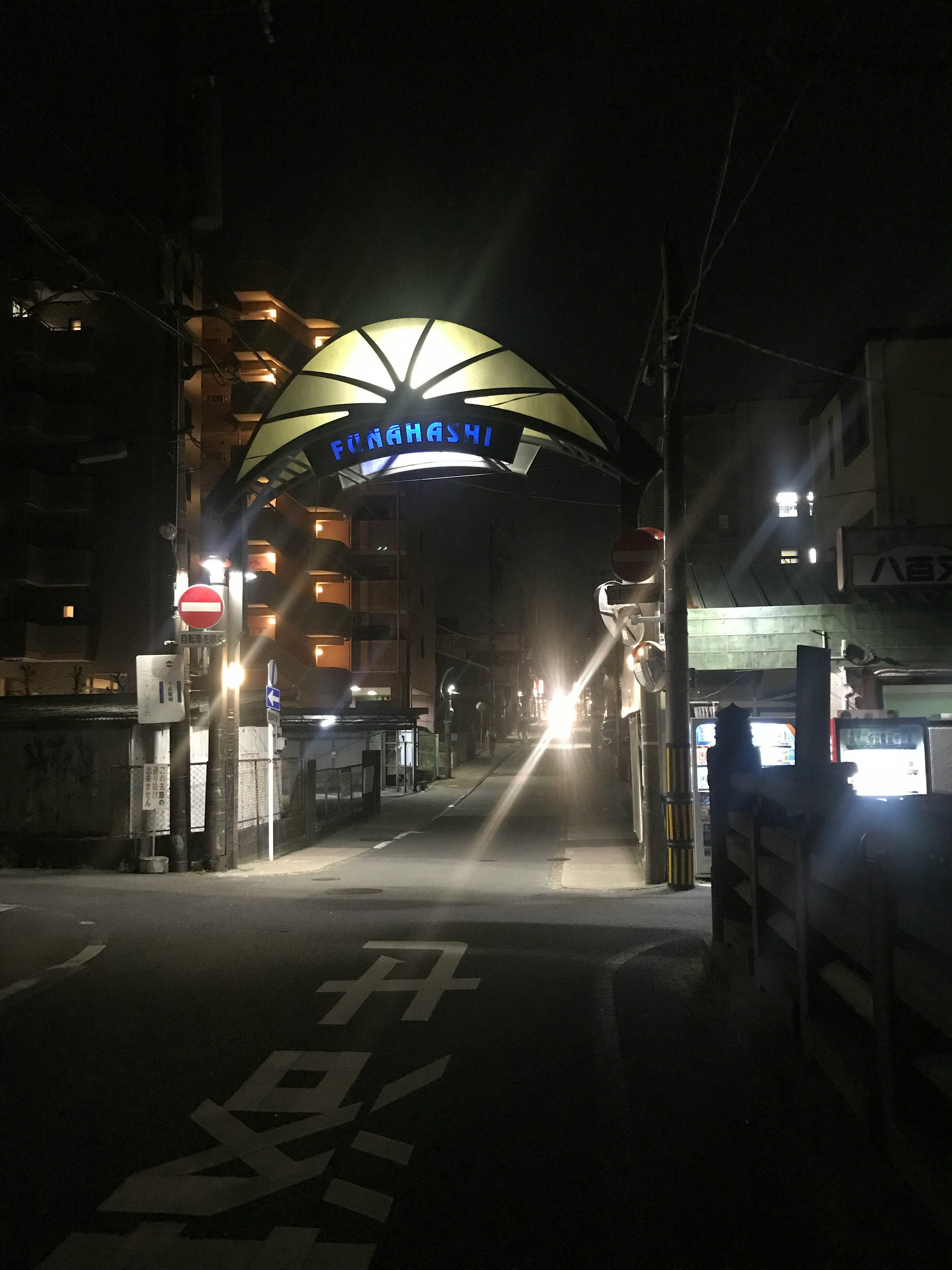 夜の高架下に伸びる街灯と車道のある路地