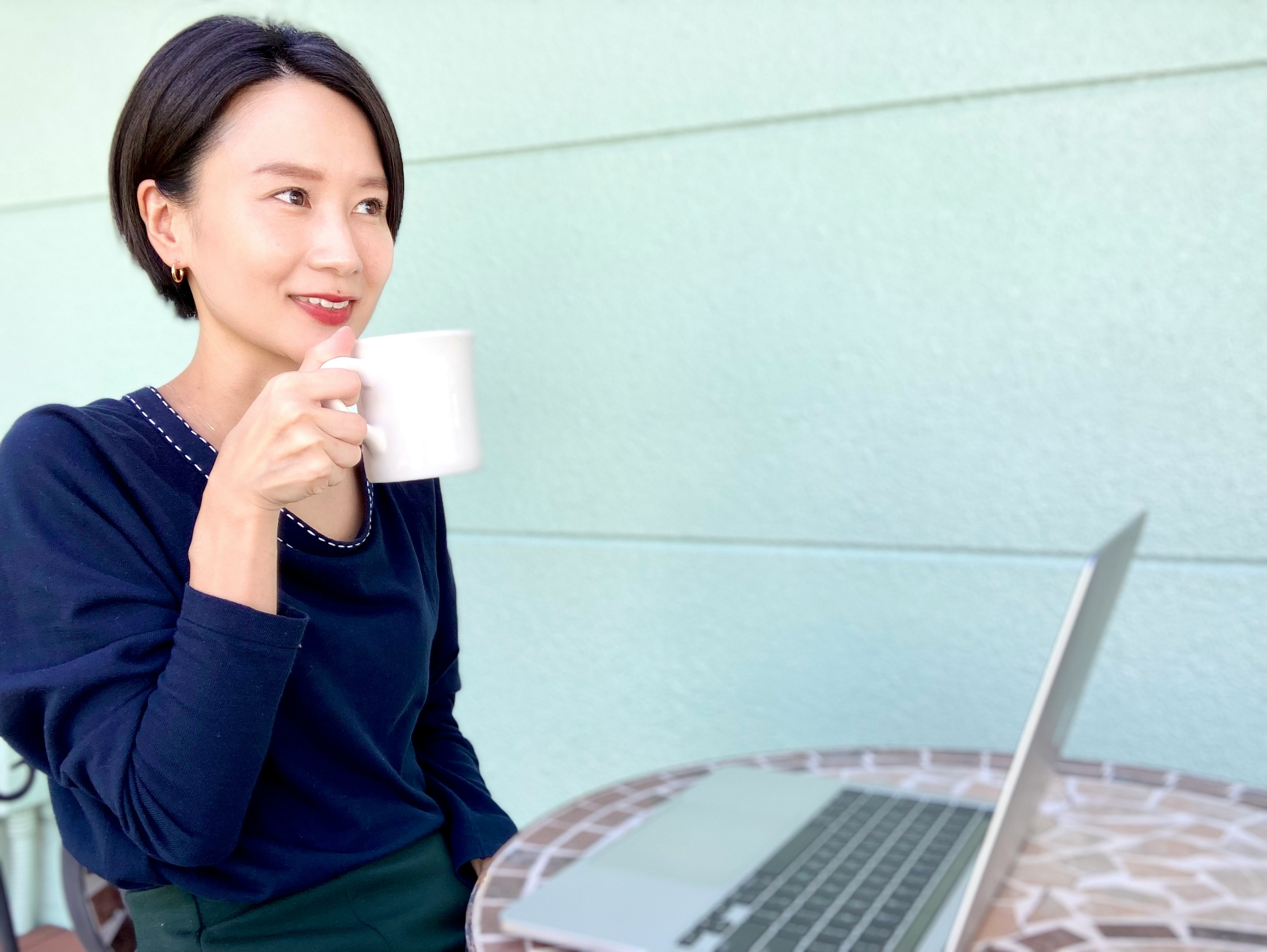 donna con una tazza accanto a un laptop