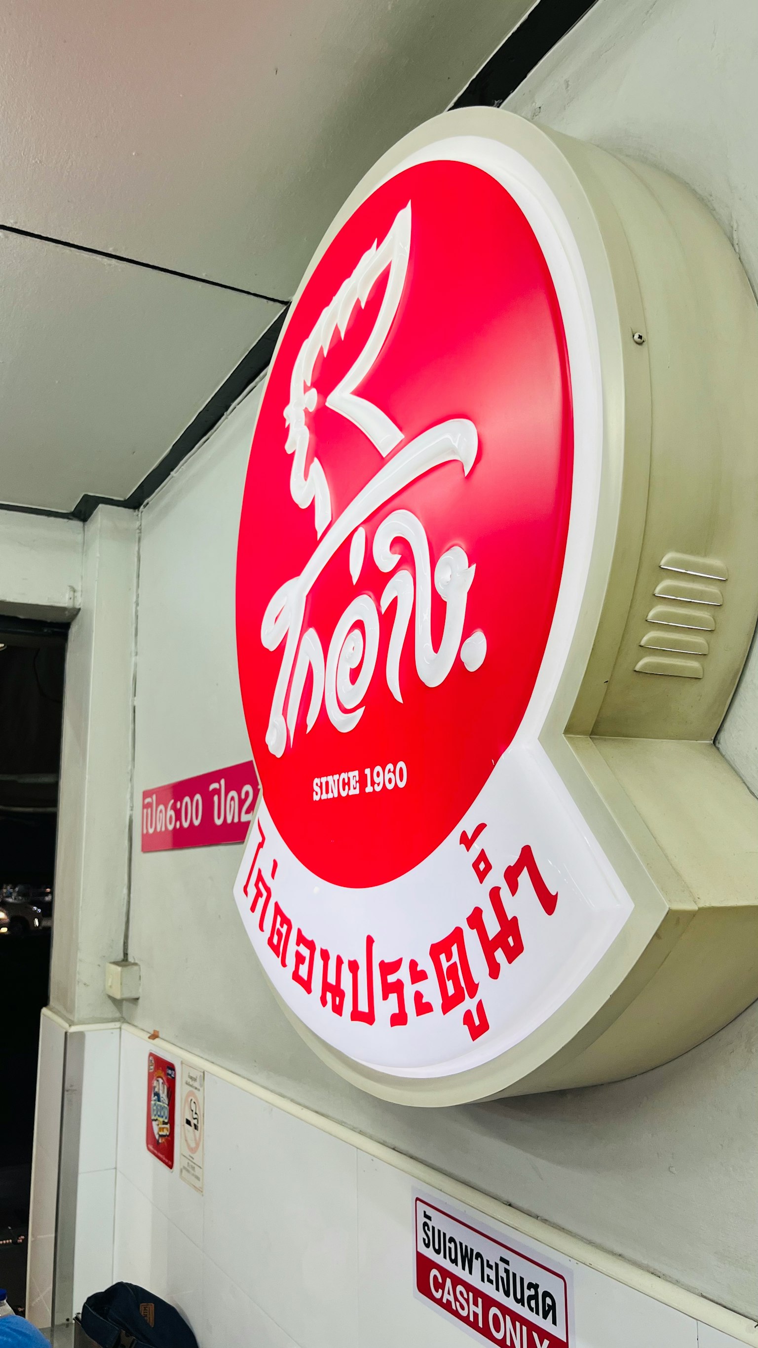Cartel rojo redondo con texto blanco de un logotipo de restaurante tailandés