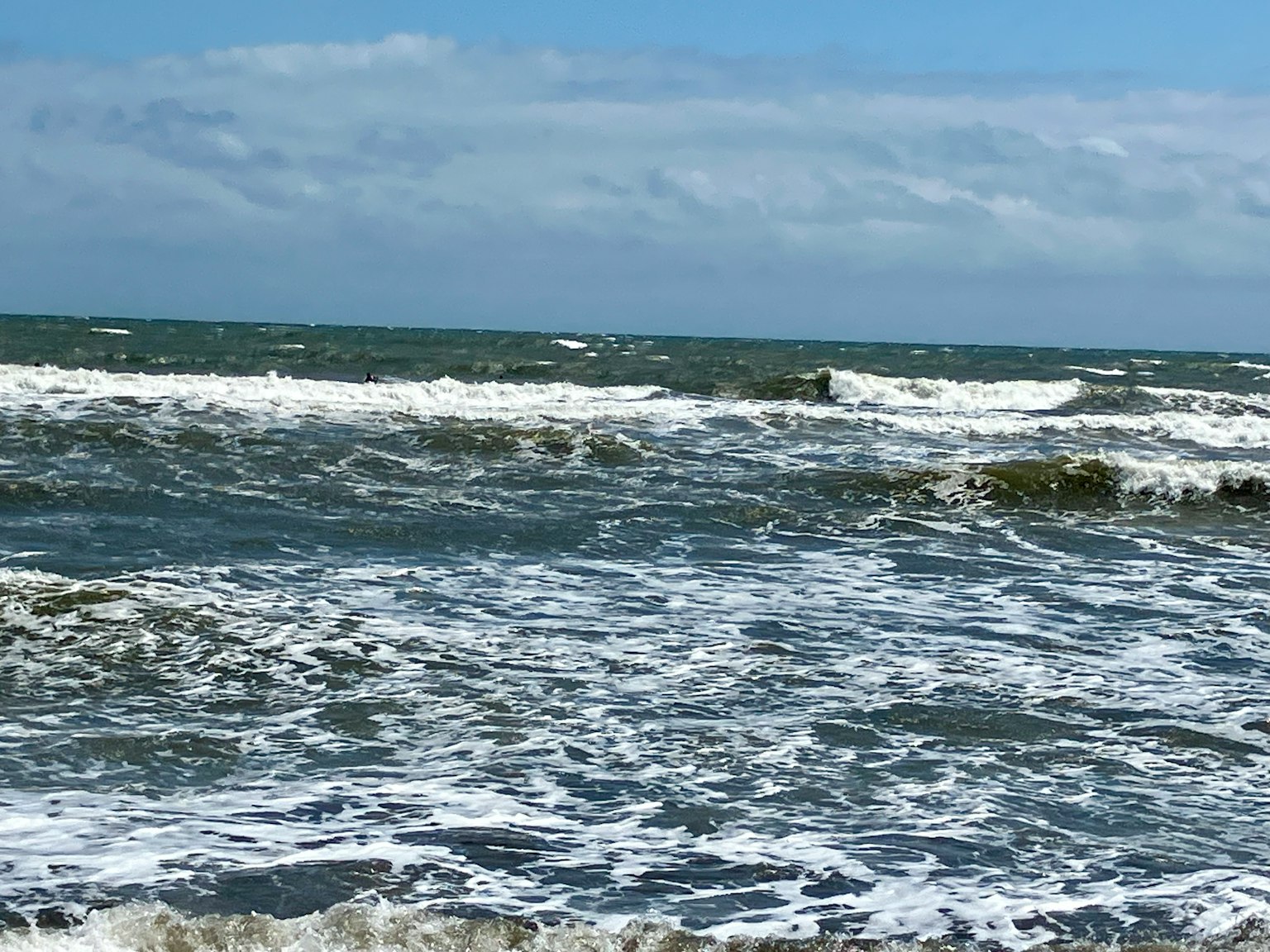 Vagues s'écrasant sur le rivage sous un ciel bleu