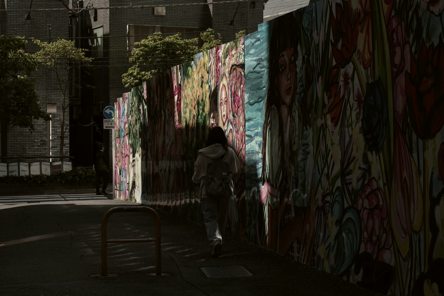 走在五彩斑斓涂鸦墙旁的人影