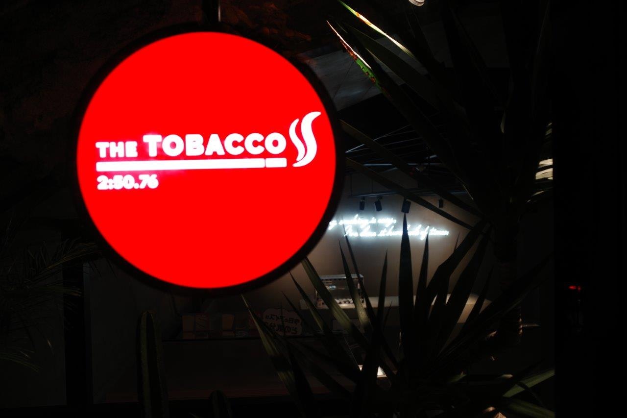 赤い看板「THE TOBACCO」前の夜の路地のような外観