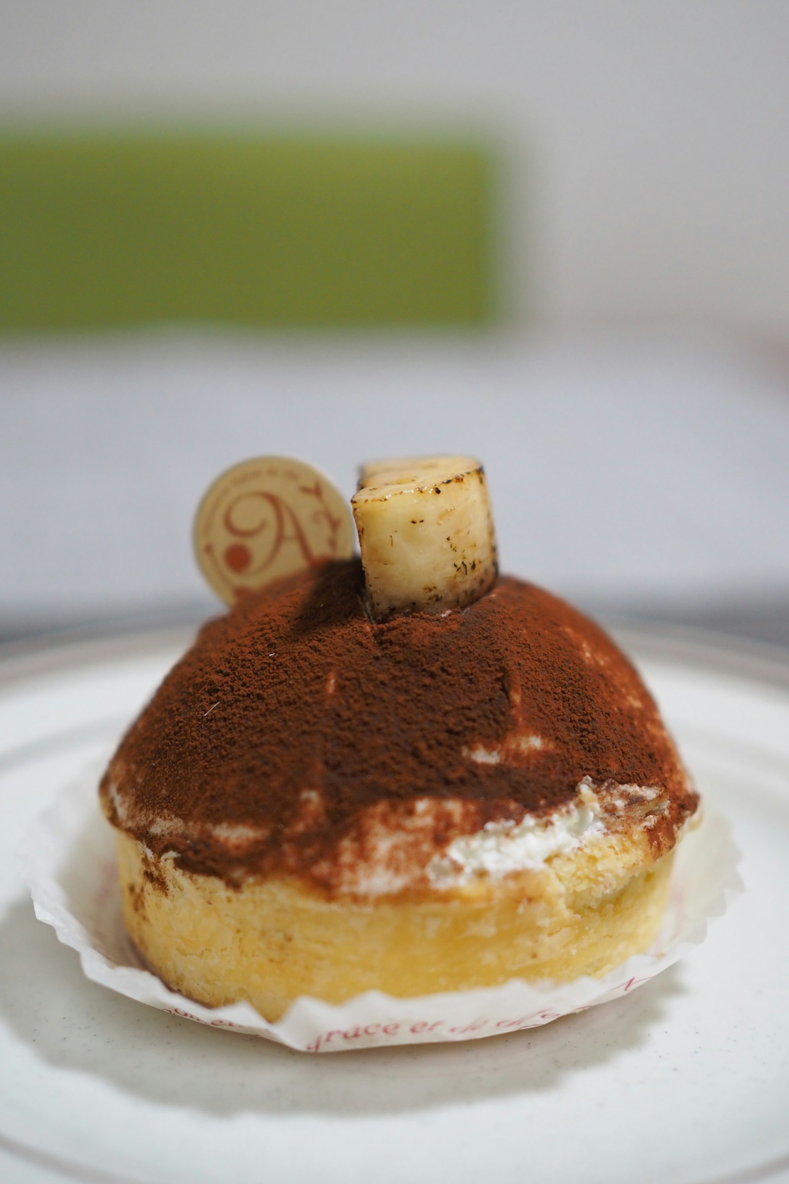 Un dessert ressemblant à un tiramisu est placé sur une assiette avec des couches crémeuses et une garniture de cacao
