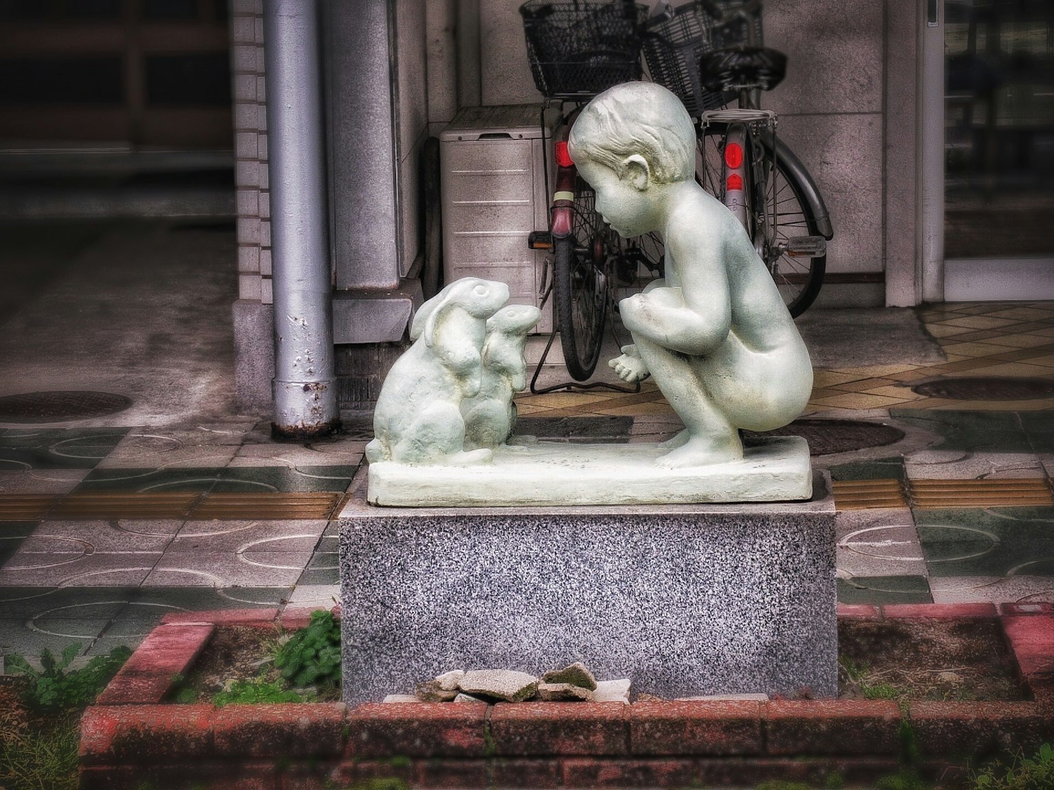 Sculpture of a child interacting with a rabbit in a park