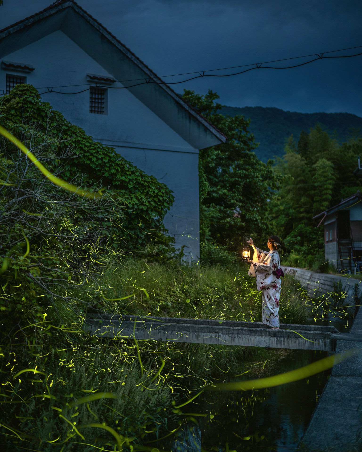 Una mujer en kimono sosteniendo una linterna en un paisaje nocturno