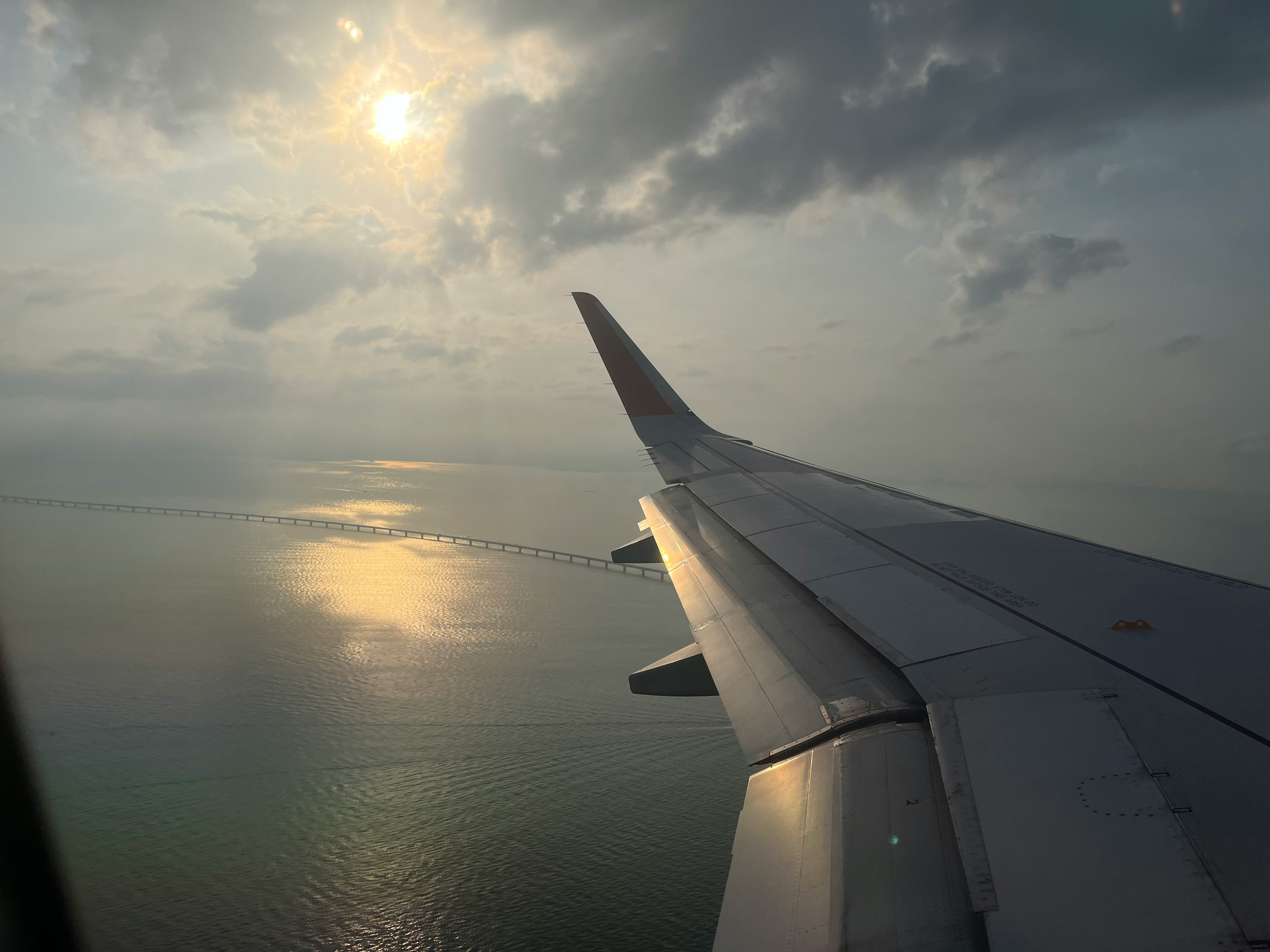 飛行機の窓から見える海と夕焼けの空