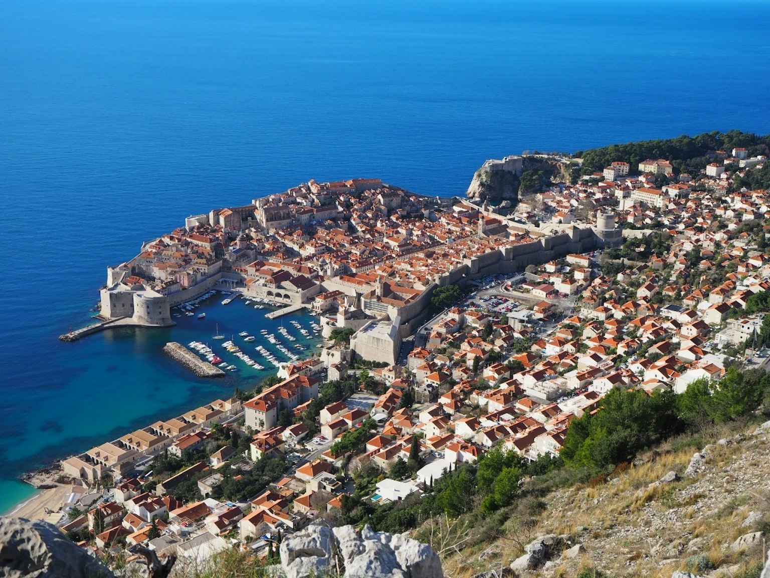 Aerial view of a historic coastal town with terracotta roofs and a marina