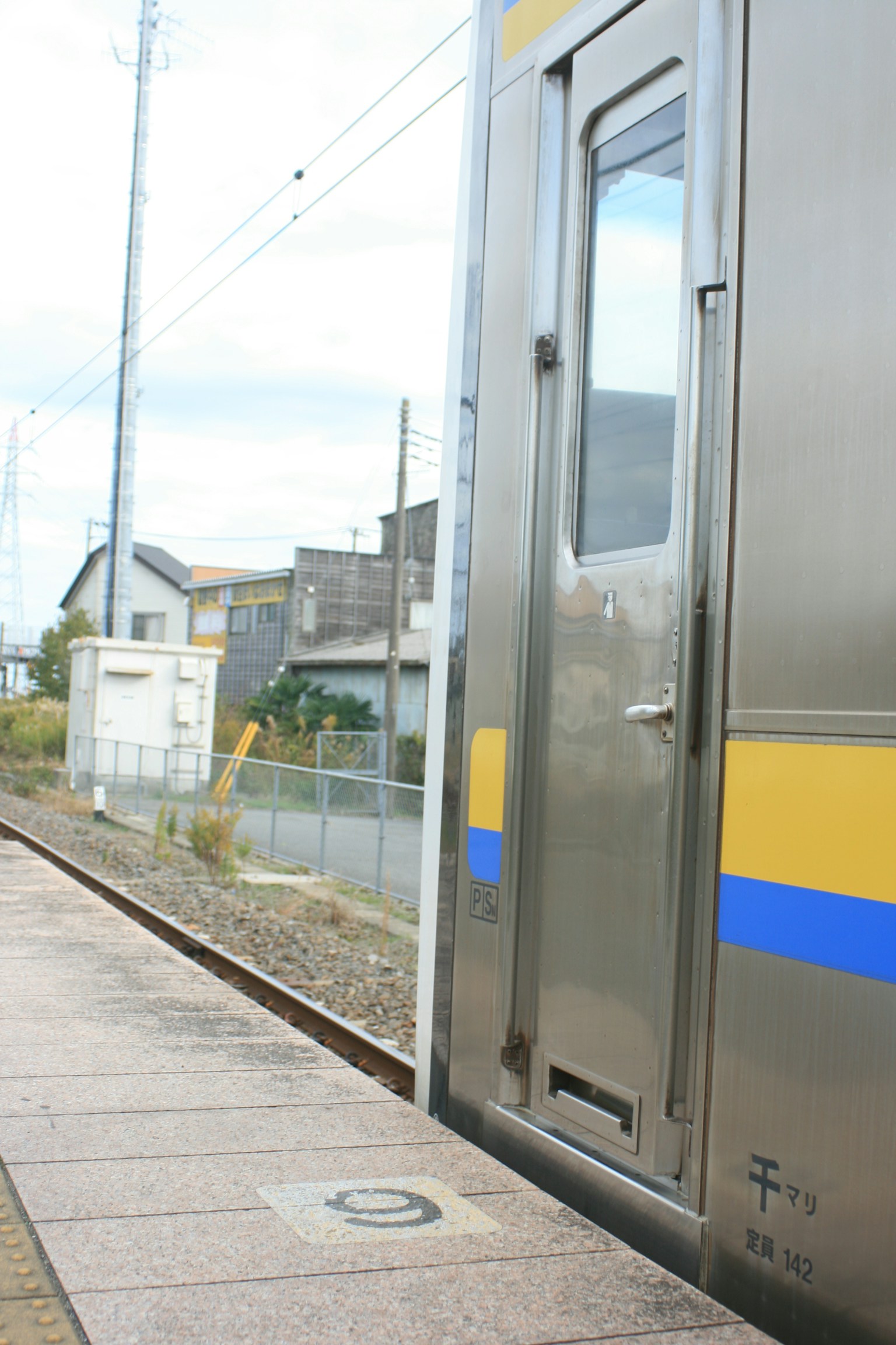 Pemandangan samping kereta yang berhenti di platform menunjukkan rel kereta dan bangunan di sekitarnya
