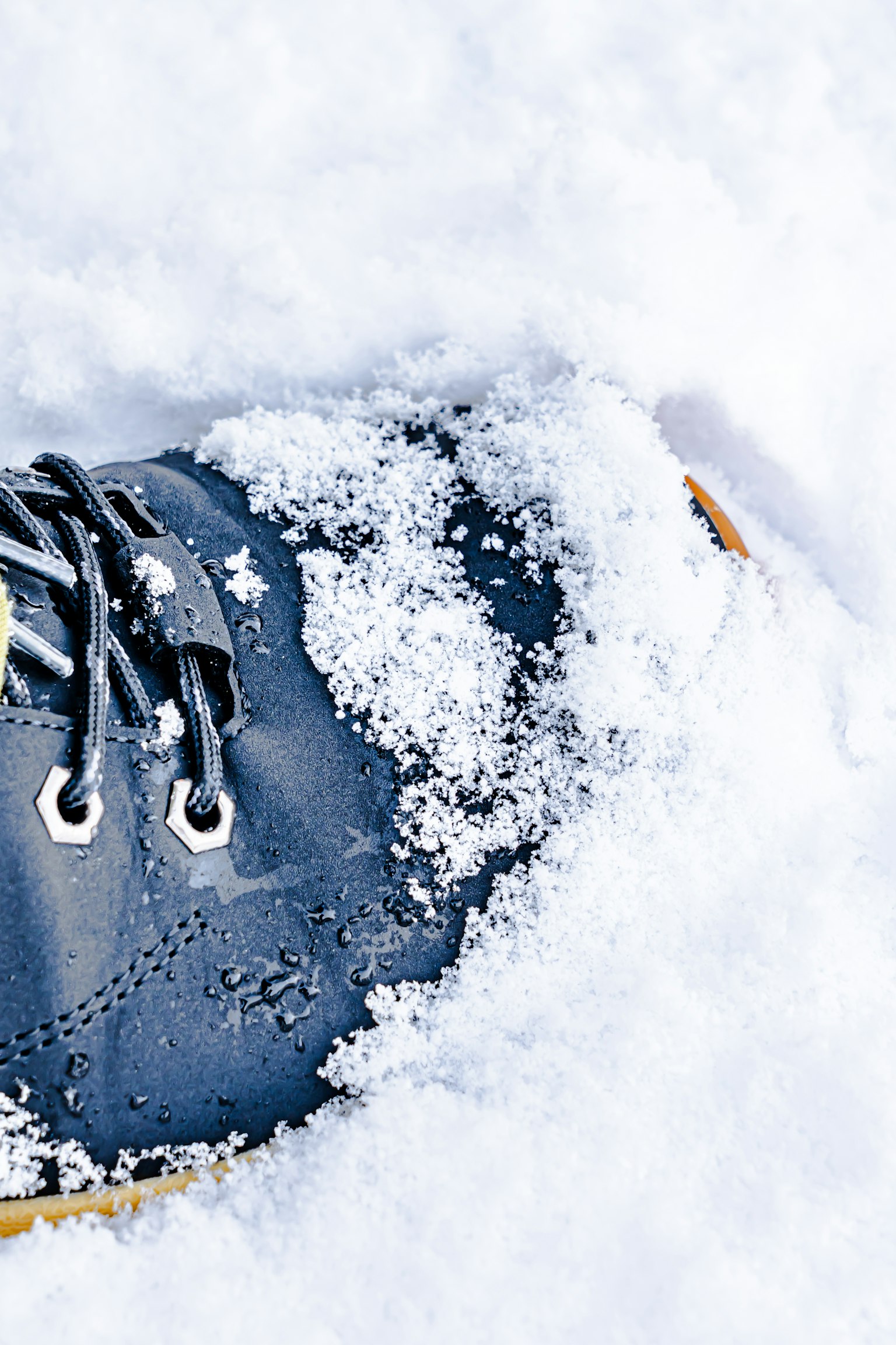 A close-up of a black shoe partially buried in snow