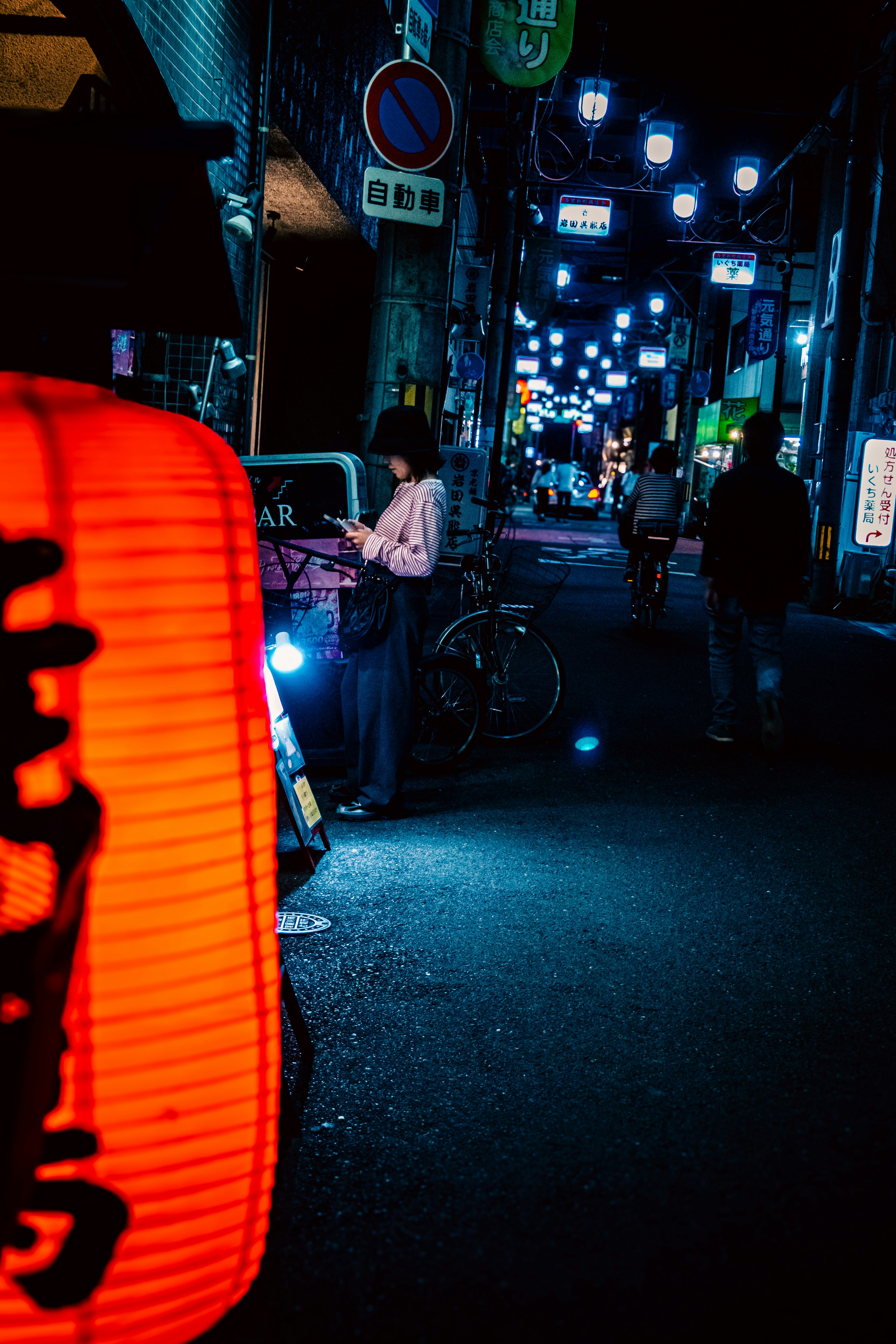 路地に並ぶ自転車と夜の街灯の光が差す商店街の通り