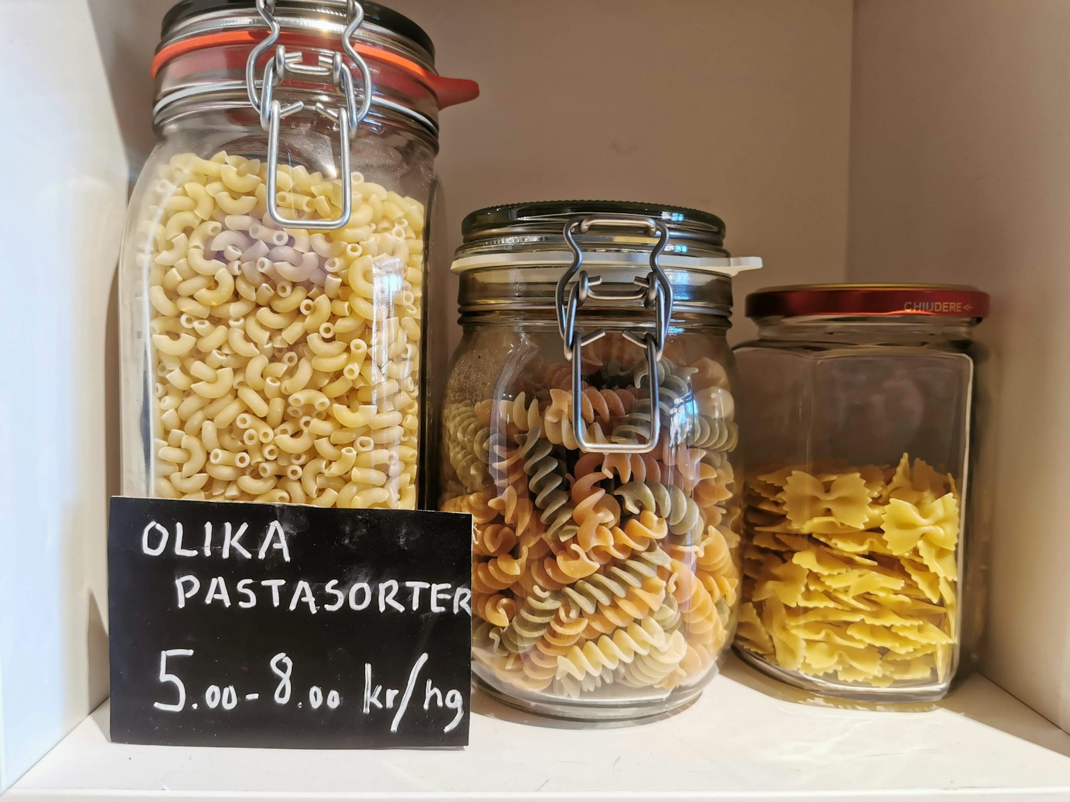 Shelves displaying various types of pasta in glass jars
