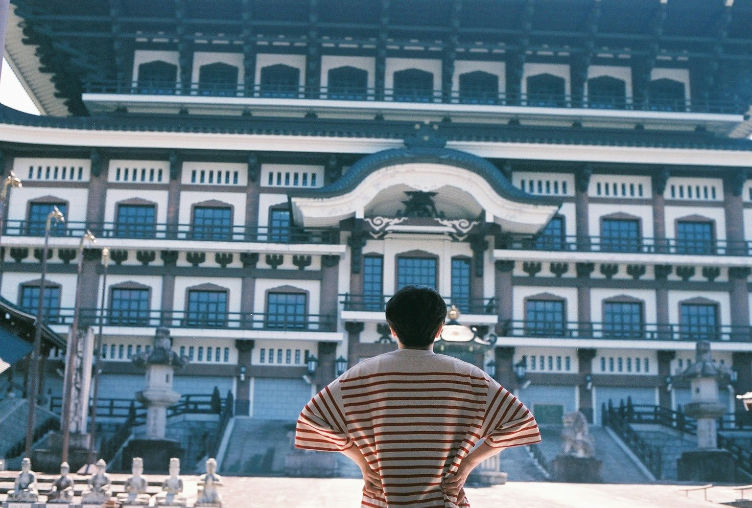 一个人站在传统建筑前面，建筑设计精美