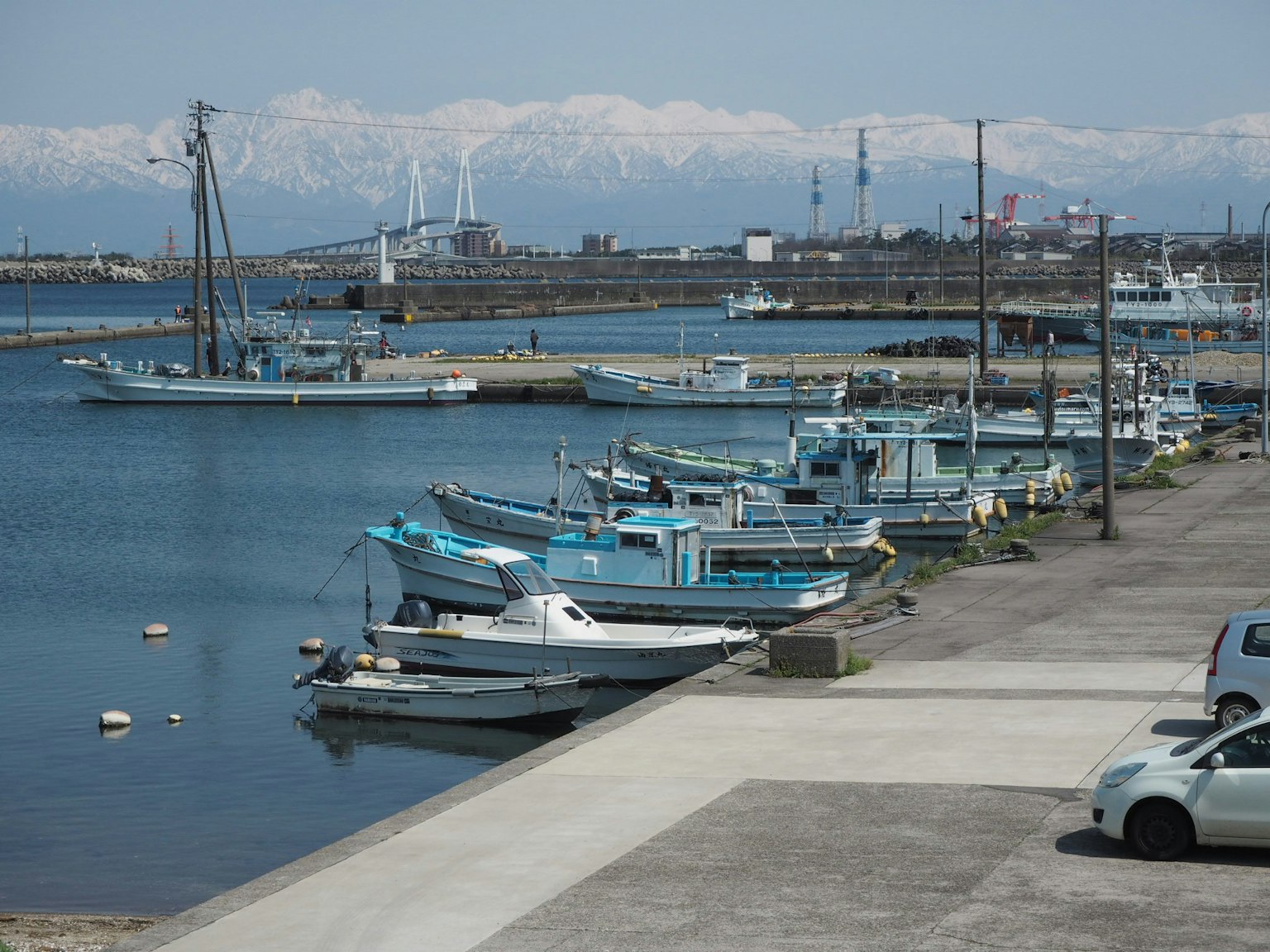 Blaue Fischerboote im Hafen mit schneebedeckten Bergen im Hintergrund