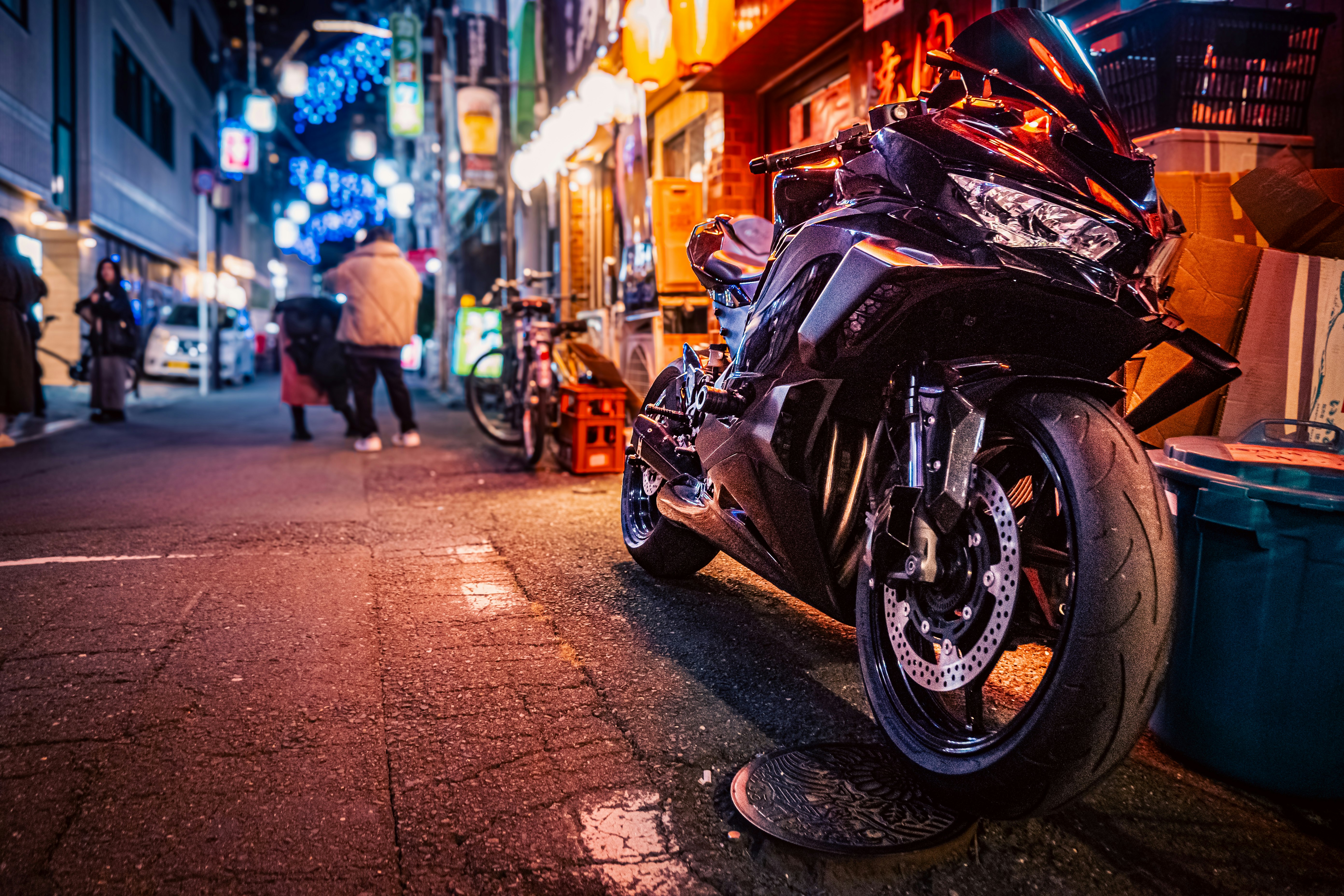 夜の路地に停まるバイクとネオンの街並み