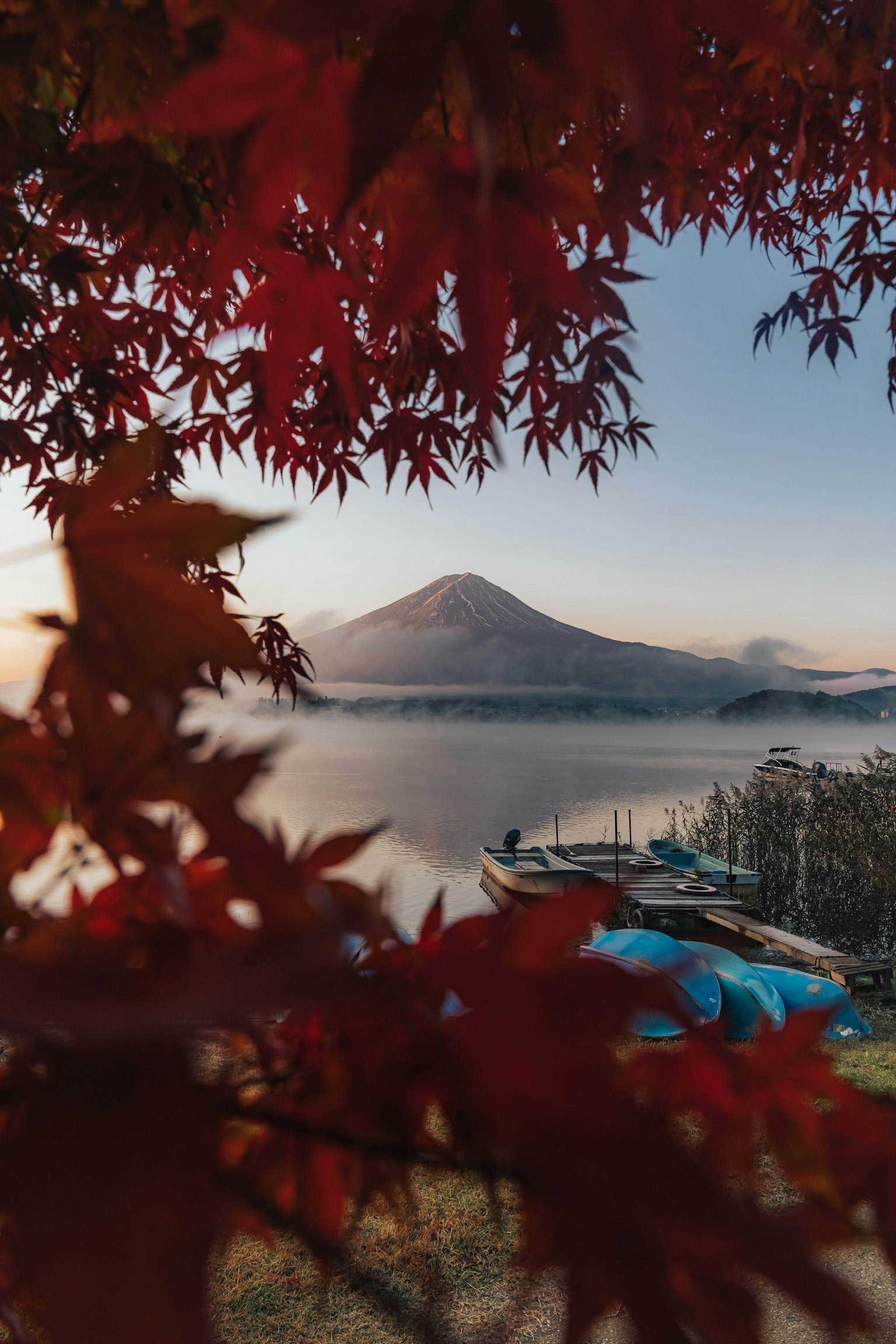 Pemandangan gunung dan danau yang dikelilingi daun musim gugur