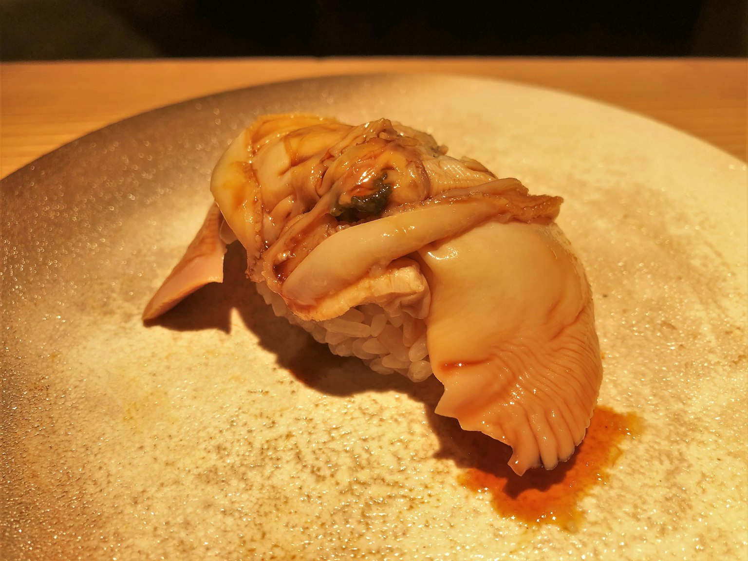 Un morceau de sushi avec un gros coquillage sur une assiette