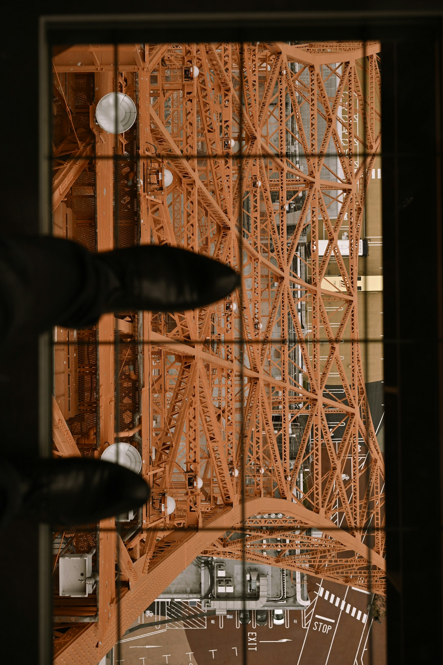 Blick von oben auf den Tokyo Tower mit der Stahlstruktur und den Schuhen einer Person