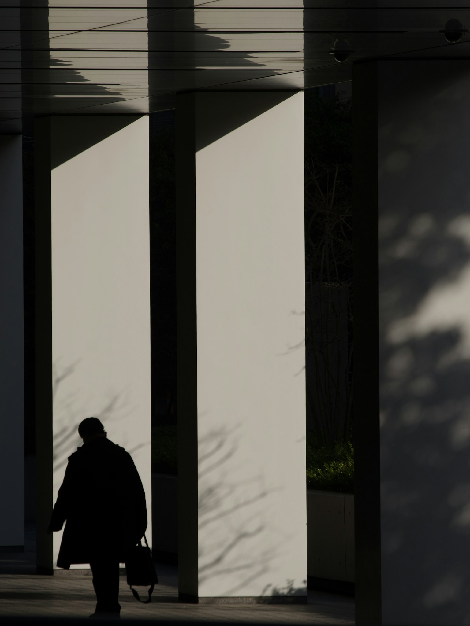 Silhouette di una persona che cammina tra muri bianchi