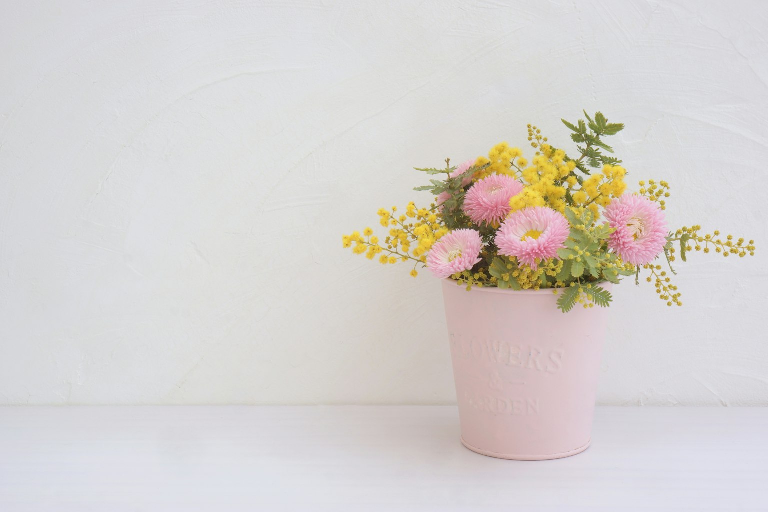 Un bouquet avec des fleurs roses et des fleurs jaunes dans un pot rose