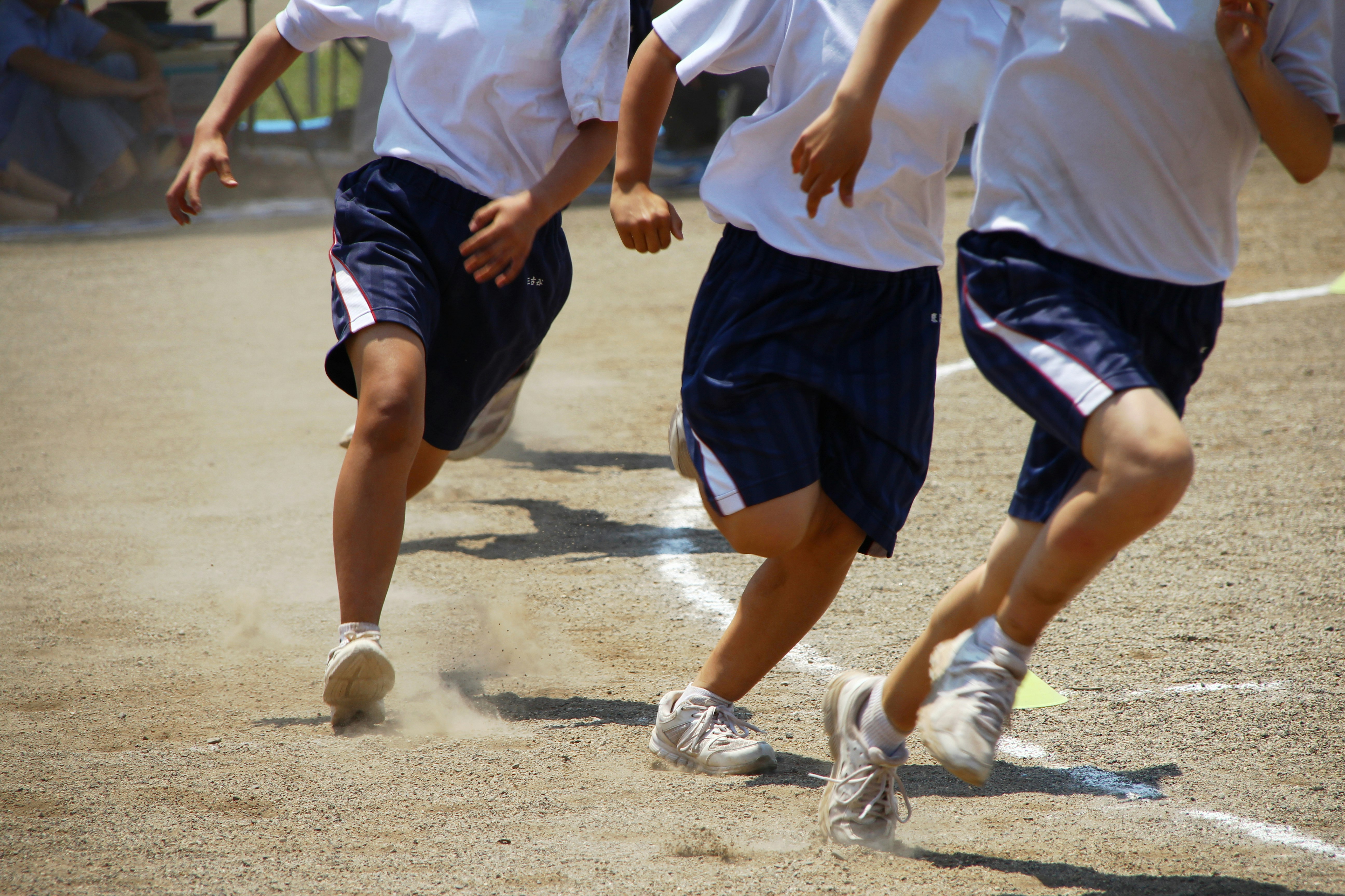 校庭で走る小学生の徒競走（後ろ姿）