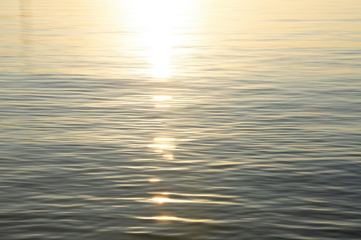 Superficie de agua tranquila reflejando la luz del atardecer